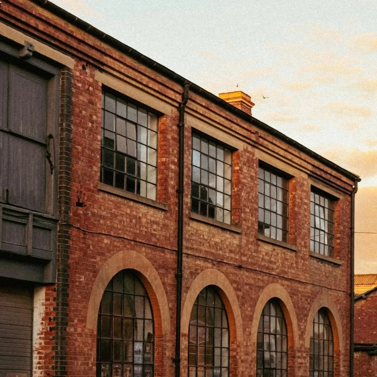 Brick industrial building with large arched and rectangular windows.