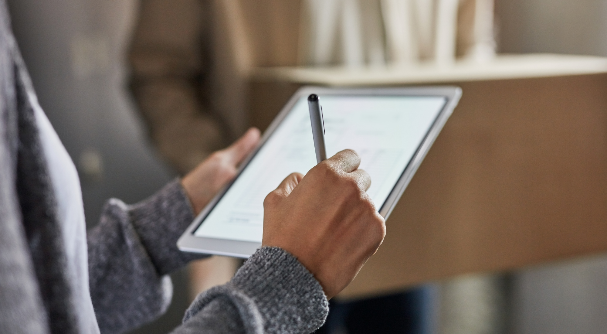Persona usando un tableta y un bolígrafo para tomar notas en un entorno interior.