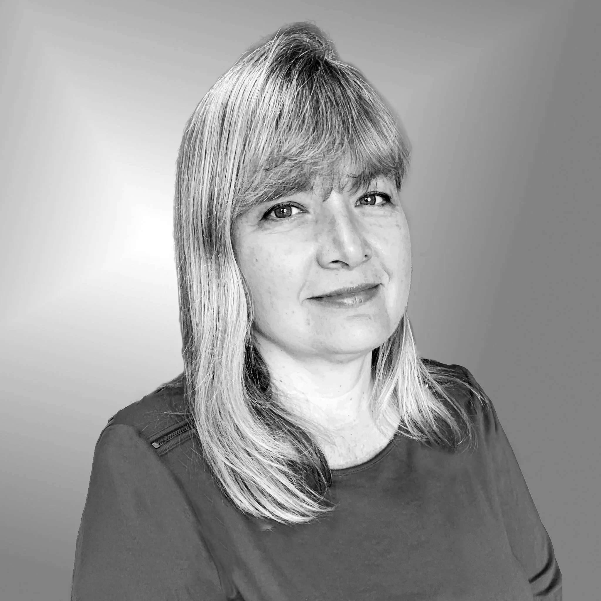 Black and white portrait of a woman with blonde hair, smiling slightly, wearing a dark top with shoulder details, against a gradient background.