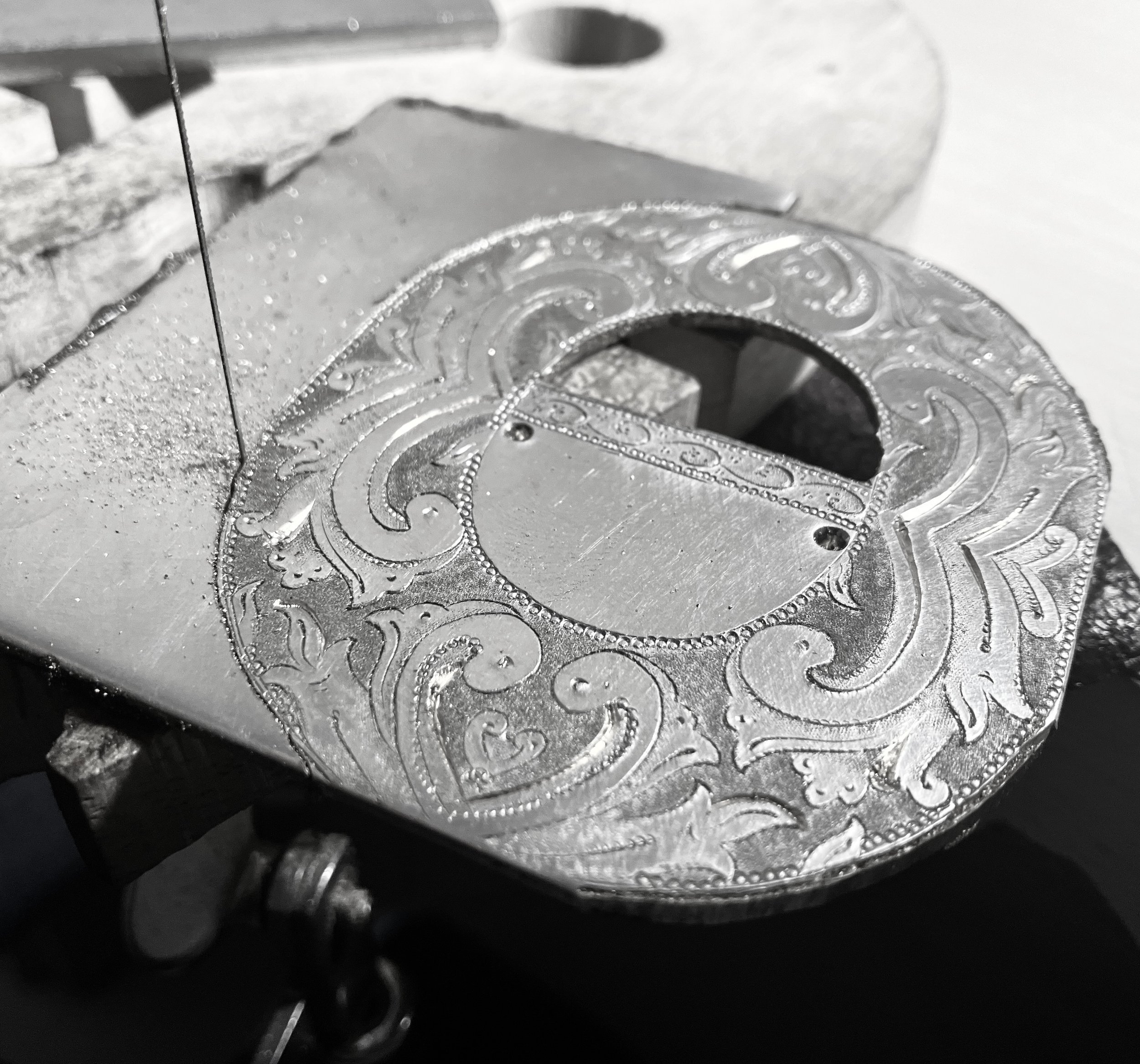 Artist sawing handmade silver belt buckles