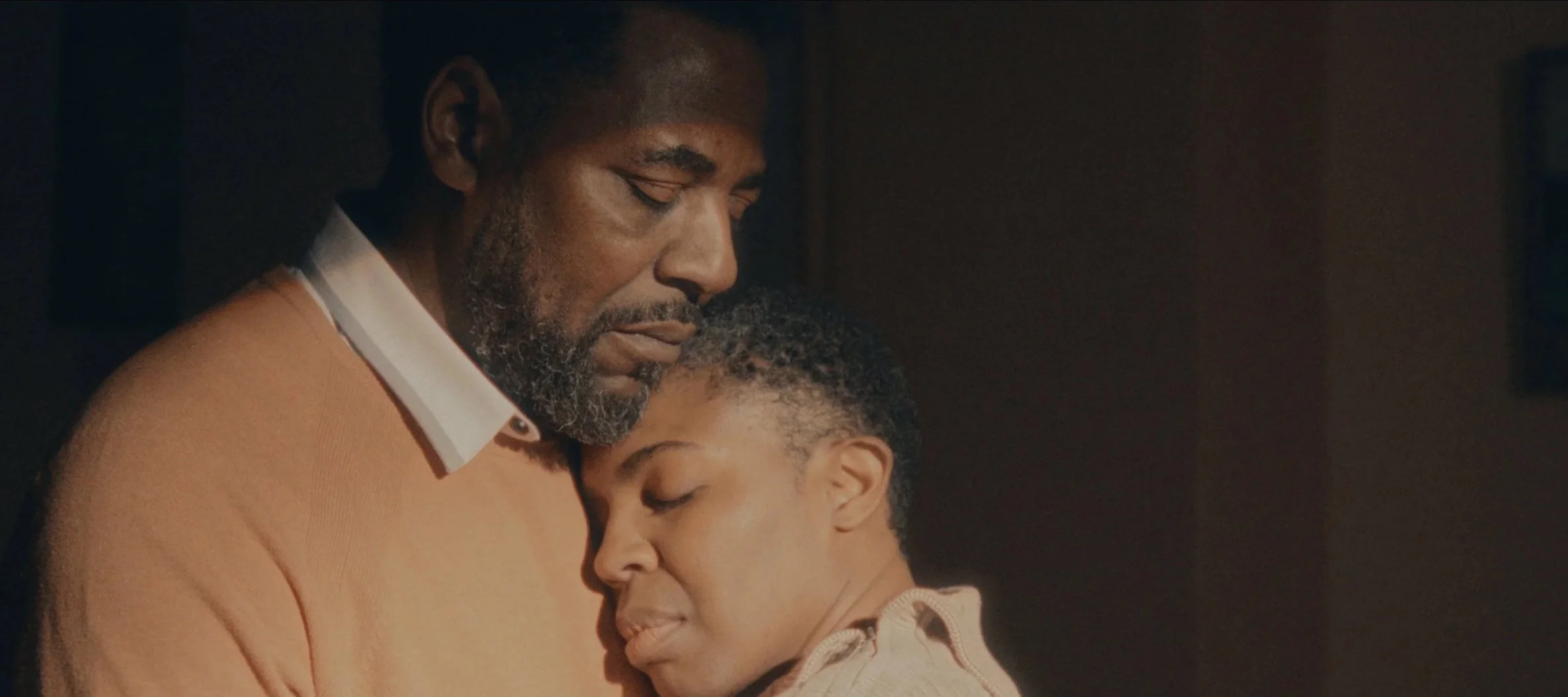 A man and woman share an emotional embrace with their eyes closed, expressing comfort and connection.