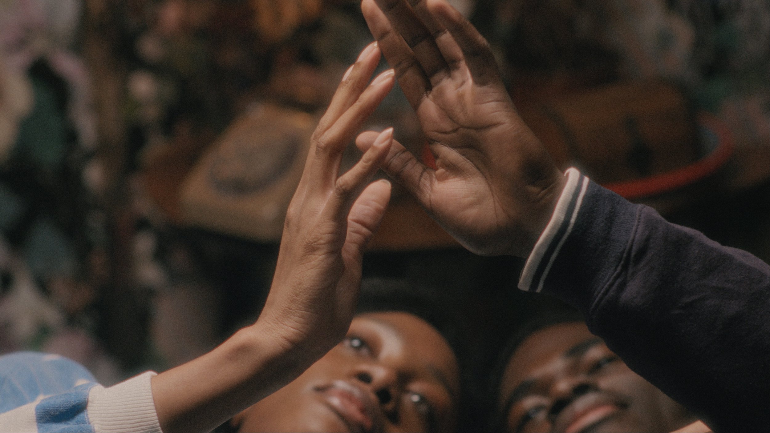Two children looking up and making a pyramid shape with their hands, smiling and lying down on the floor.