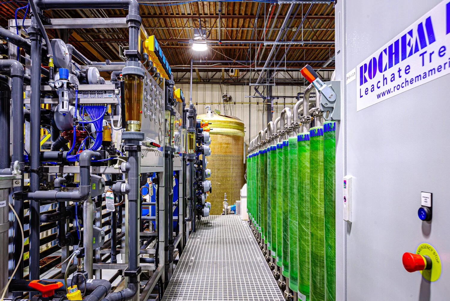 Industrial water treatment equipment with pipes, gauges, and green-filtered water tanks.