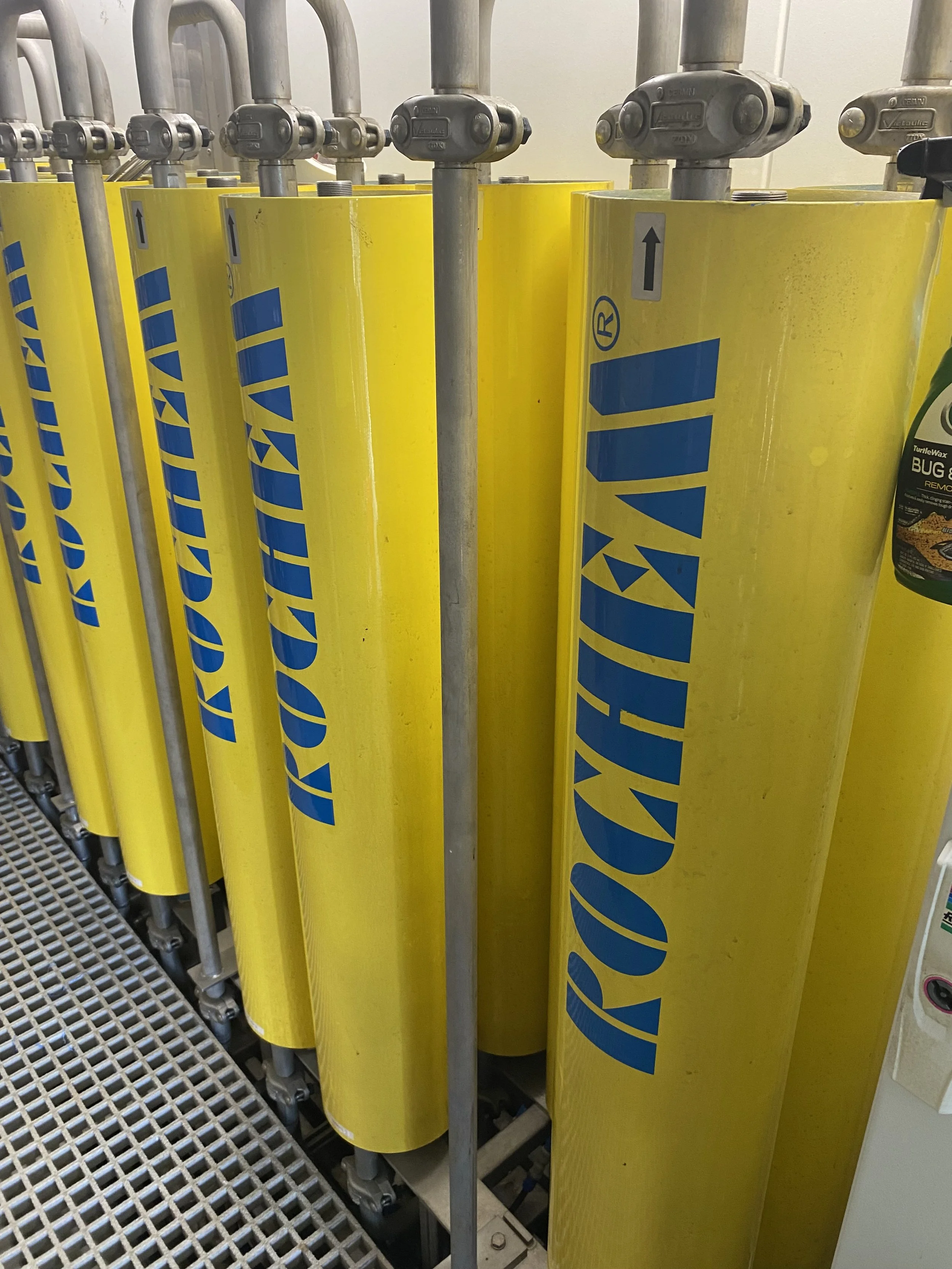 Yellow and blue KÄRCHER pressure washer rollers lined up on a metal rack inside a cleaning supply or maintenance area.
