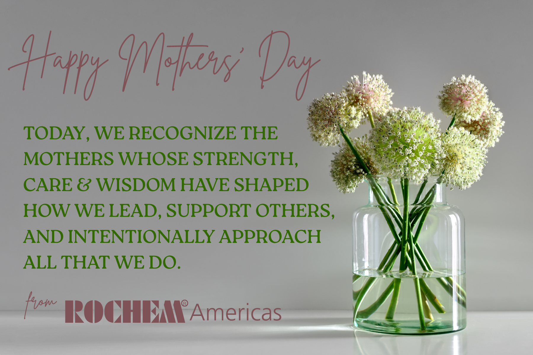 An image of a clear vase filled with clean water & holding beautiful flowers, on a white countertop, with a Mother's Day Message.