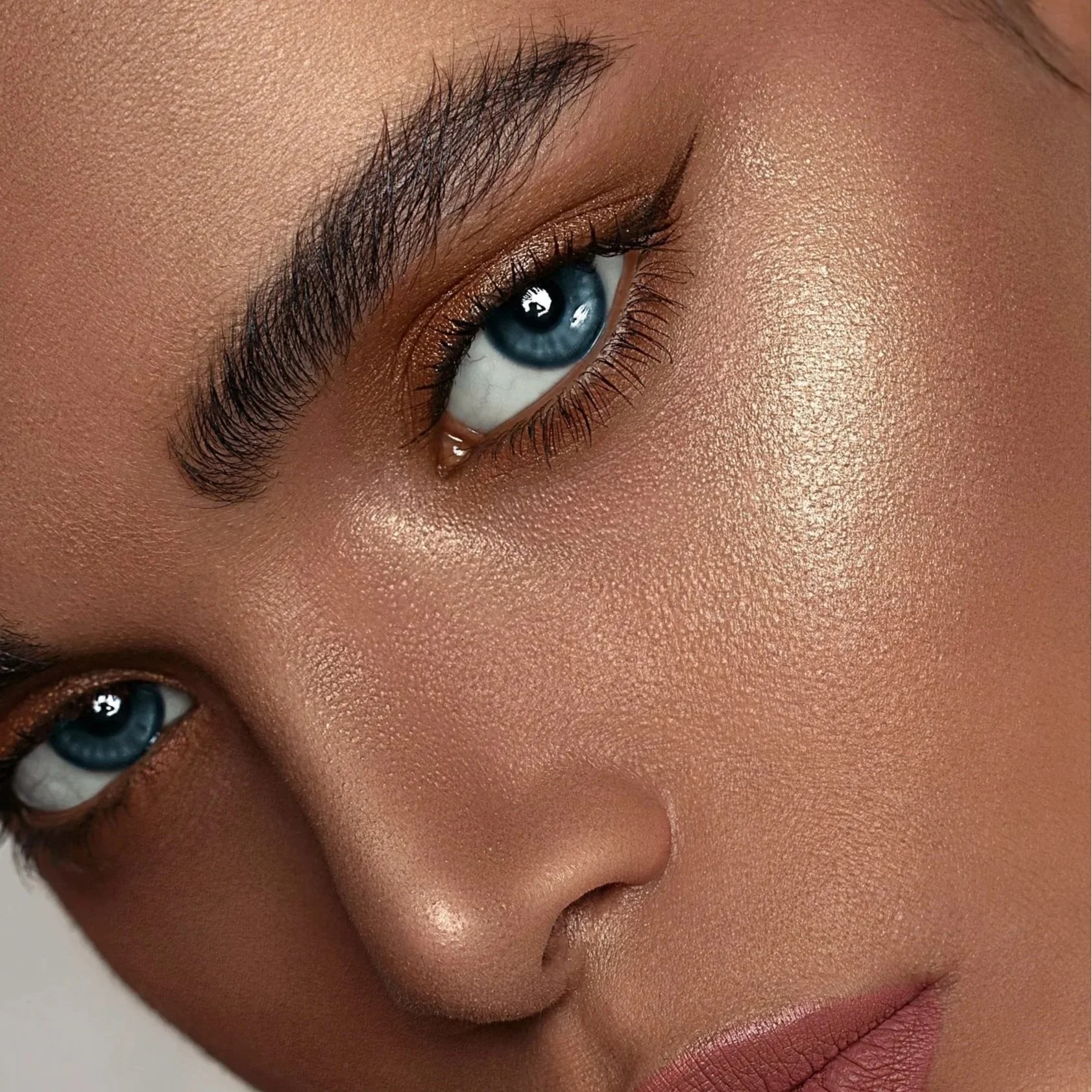 Close-up of a woman's face focusing on her blue eyes, with detailed makeup and smooth skin.