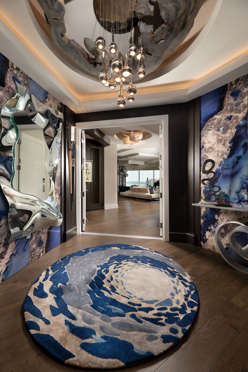 Modern Penthouse elevator entry by Gloria Black Design- dramatic galactic-inspired interior featuring monumental hand-selected galaxy glass wall panels, bespoke round area rug custom-designed by Gloria Black in deep cobalt and lunar grey, sculptural