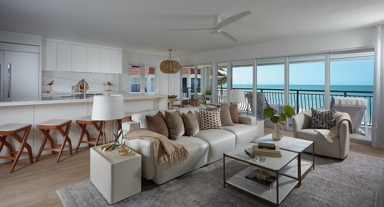 Gulfshore Getaway luxury coastal living room by Gloria Black Design — open-plan layout with floor-to-ceiling Gulf views, woven rattan pendant, Brazilian furniture, textural organic palette, and resort-style comfort, Southwest Florida interior design