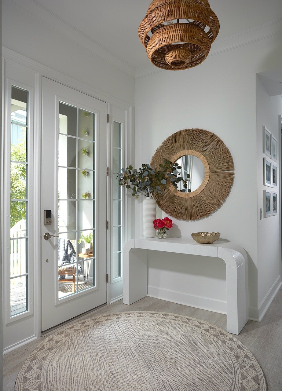 Golden Grotto bright foyer with French door, biophilic green living wall, raffia sunburst mirror and sculptural white console — Gloria Black Design Naples Florida