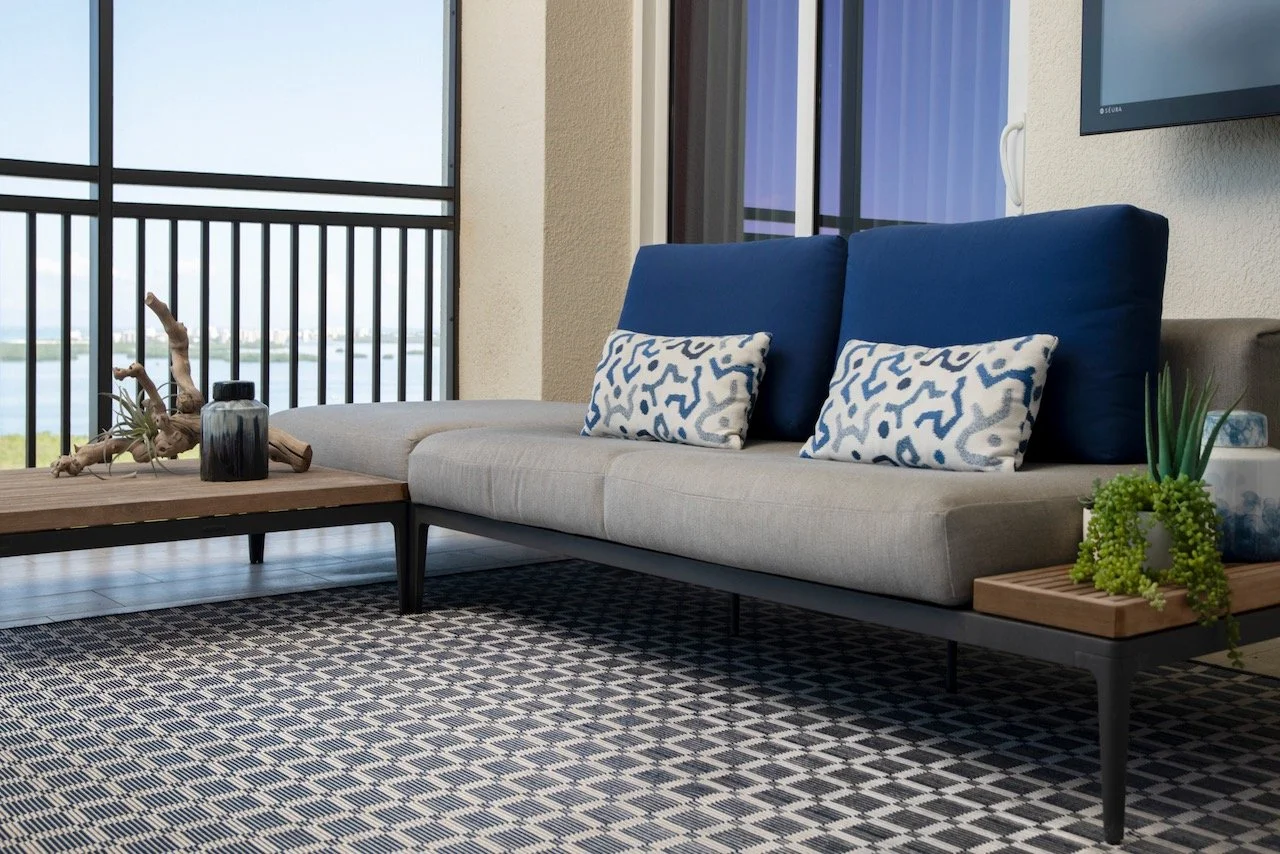 modern-penthouse-balcony-gray-sofa-blue-pillows-geometric-tile-bonita-springs-gloria-black-design.jpeg