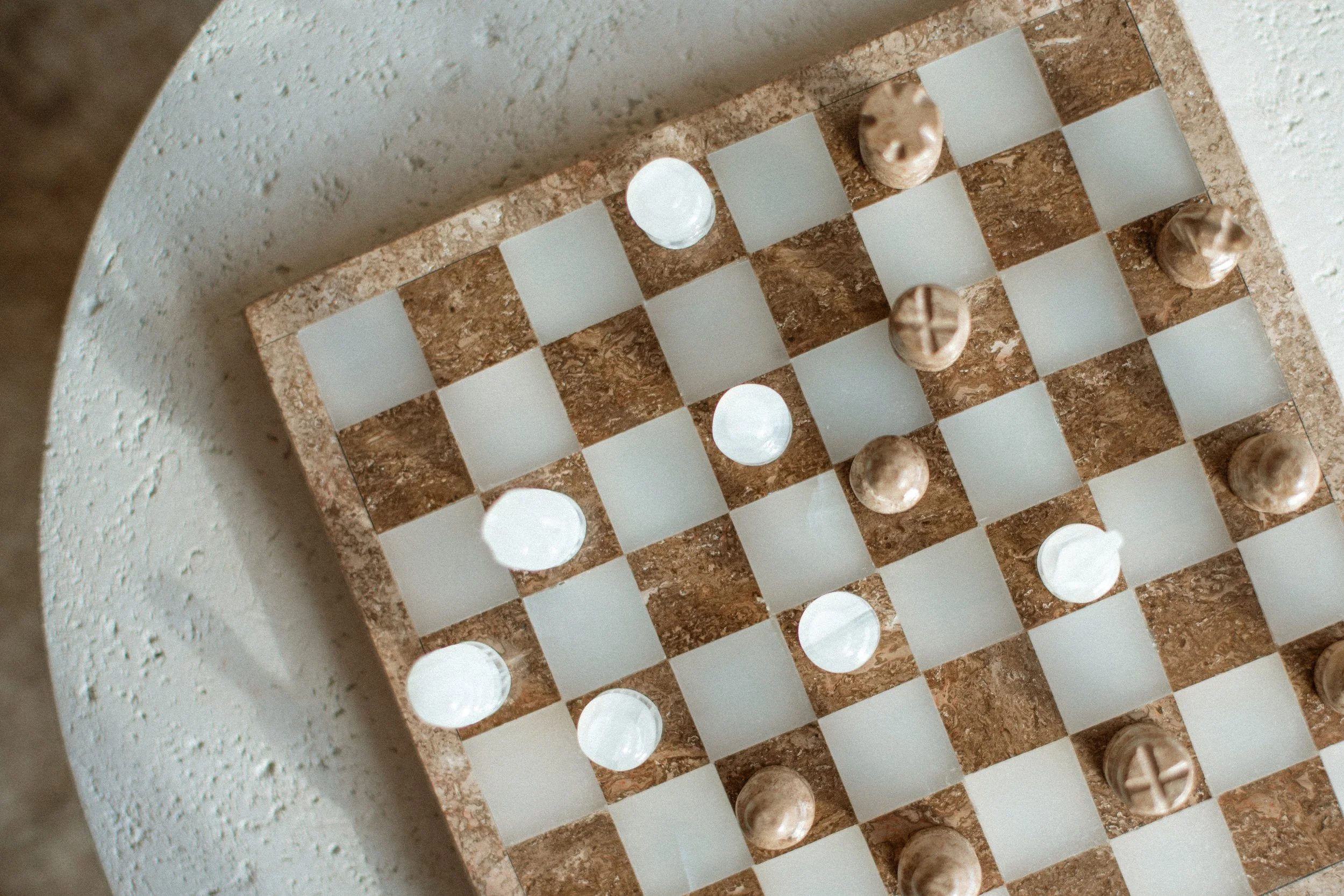 Top-down view of a chessboard with marble and crystal pieces on a round table