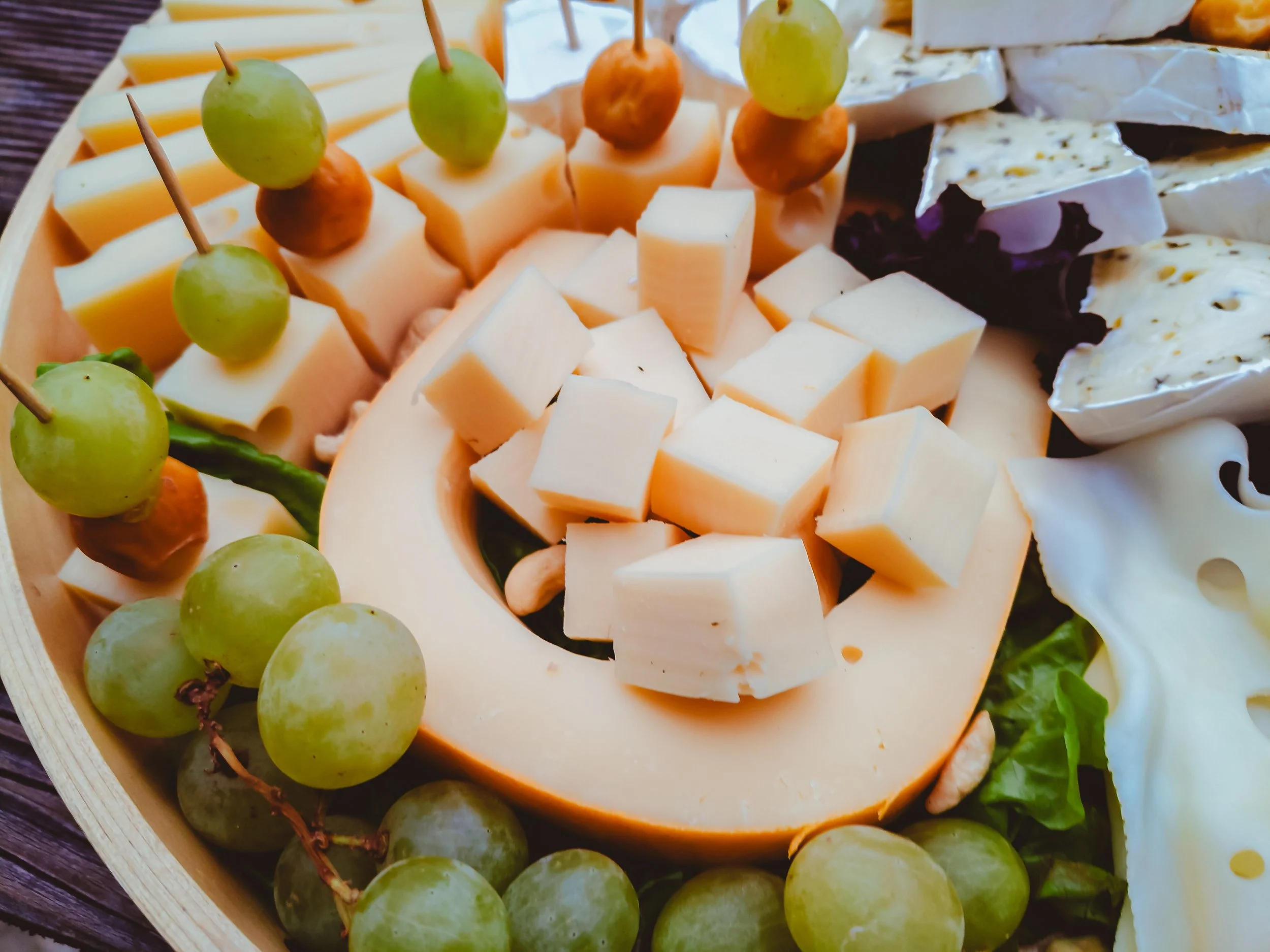 Verschiedene Käsesorten, grüner Wein und Trauben auf einem Käsebrett