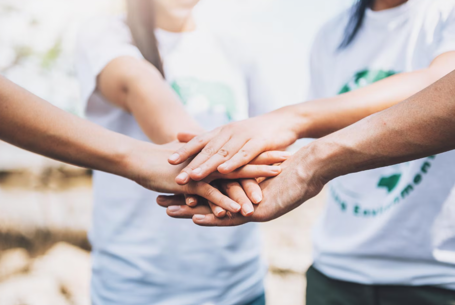 Group of people placing their hands together in a show of teamwork.