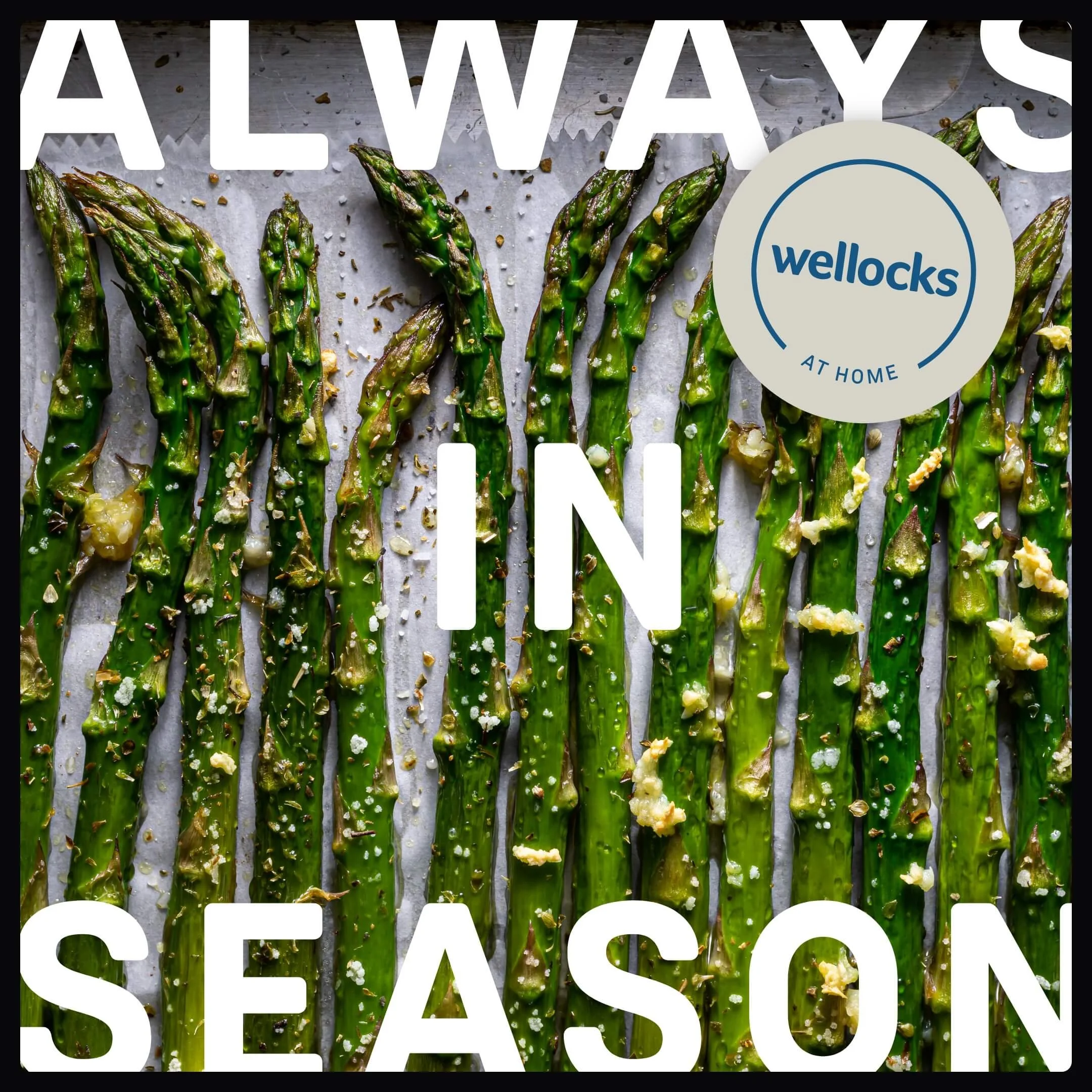 Roasted asparagus with seasonings on a baking sheet with text 'Always in Season' and a Wellocks at home logo.