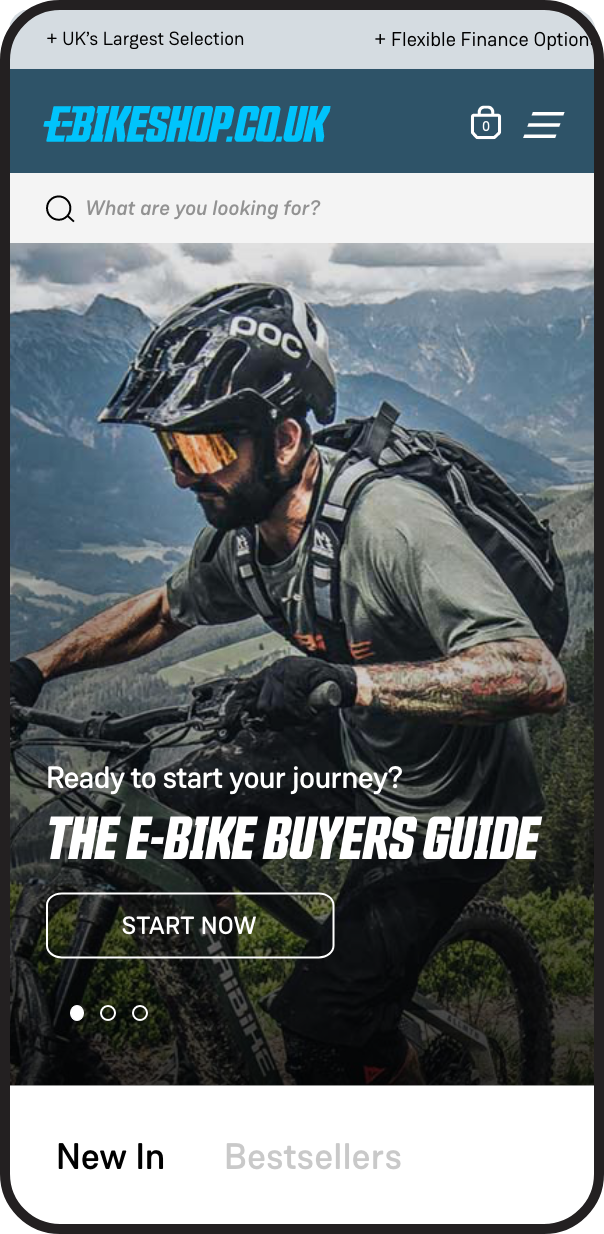 A man wearing a black helmet with 'POC' logo, sunglasses, and a gray t-shirt rides a mountain bike in a scenic outdoor landscape with mountains in the background. The screen displays a website offering e-bike guides.