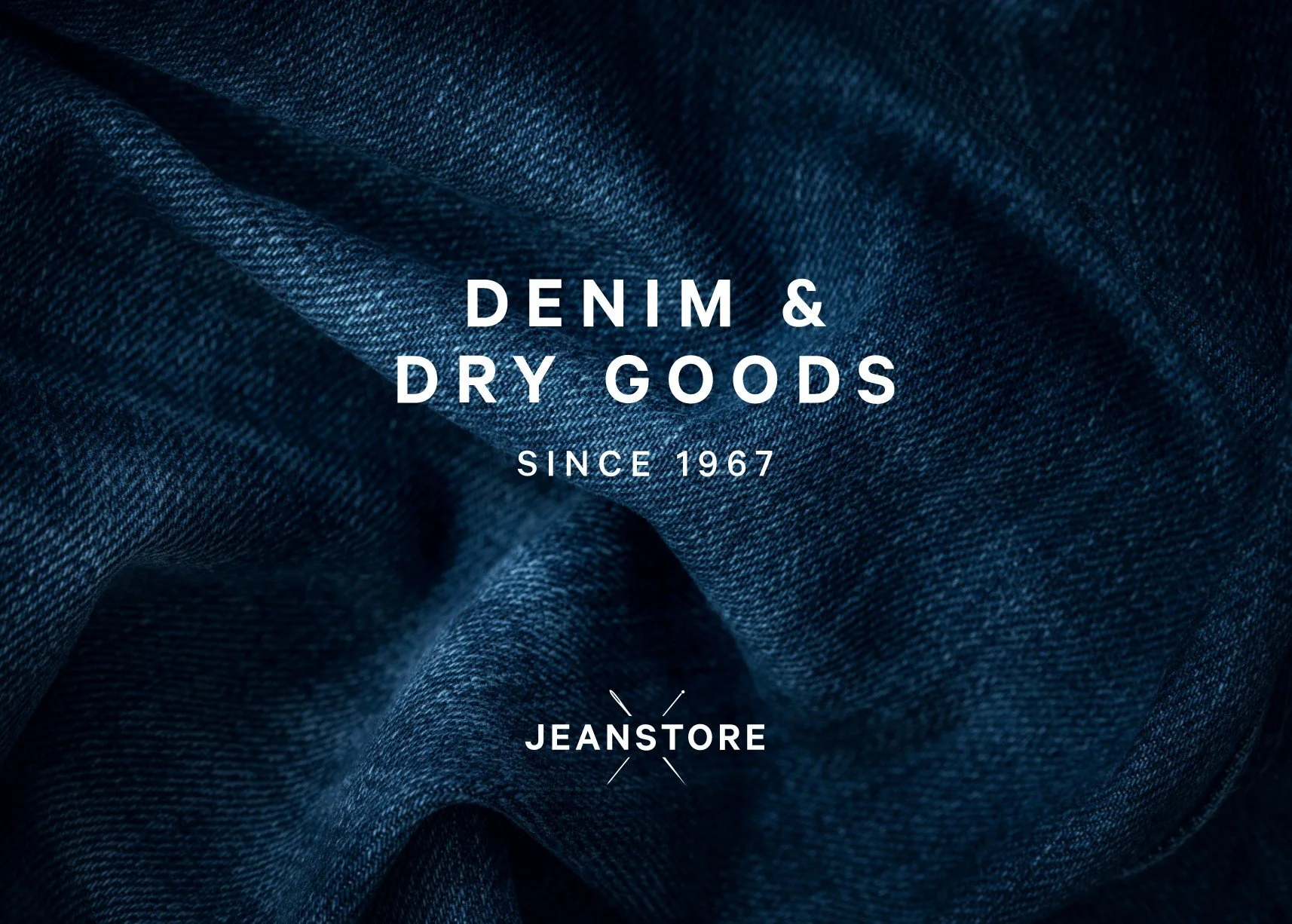 Close-up of denim fabric with text reading 'Denim & Dry Goods, Since 1967, Jeanstore'.