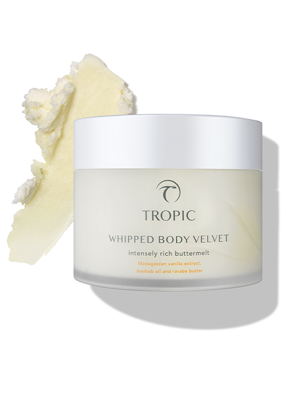 A jar of Tropic Whipped Body Velvet with a dollop of cream-colored body butter beside it on a white background.