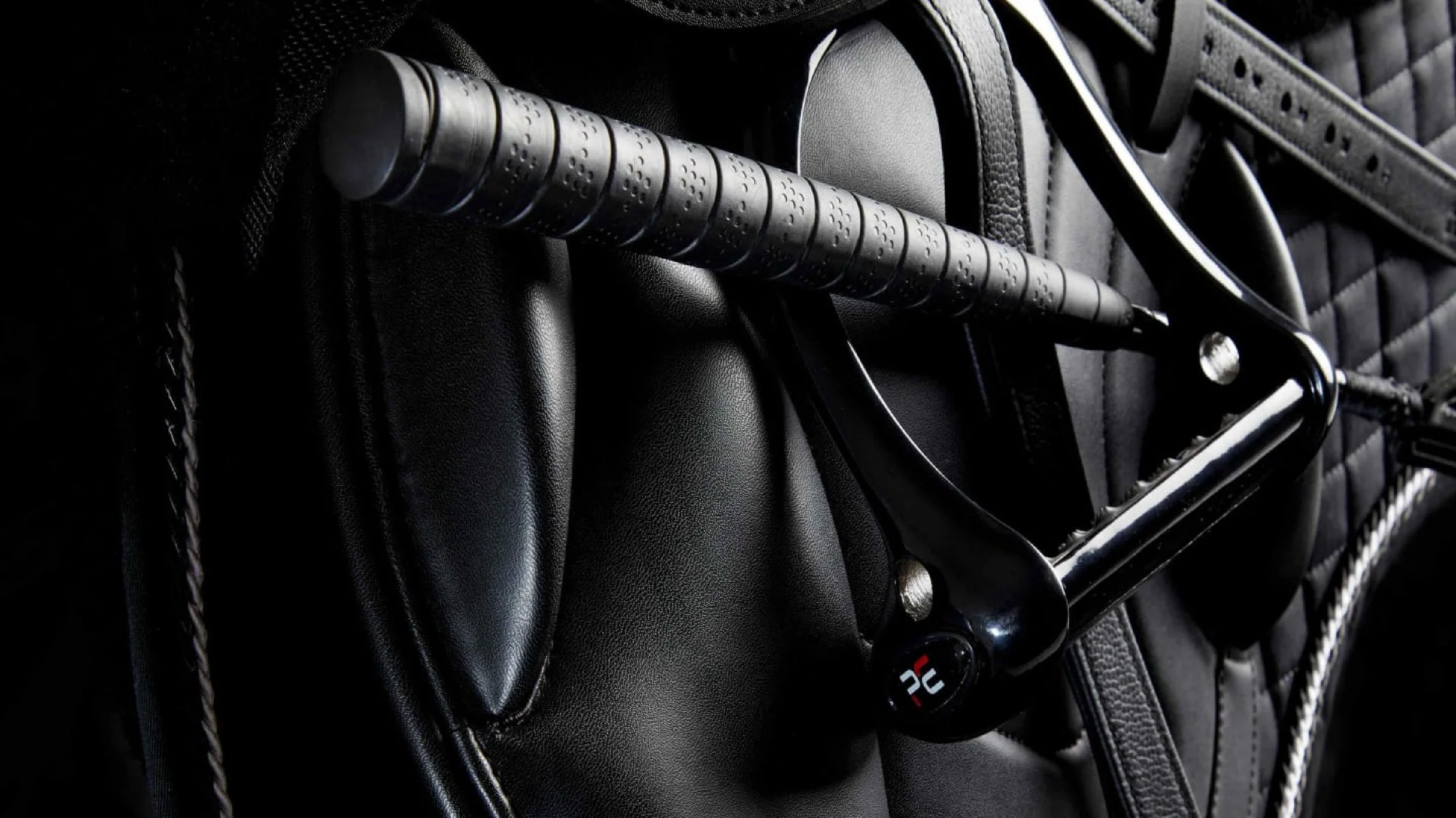 Close-up of a black golf club resting in a golf bag with black padding.