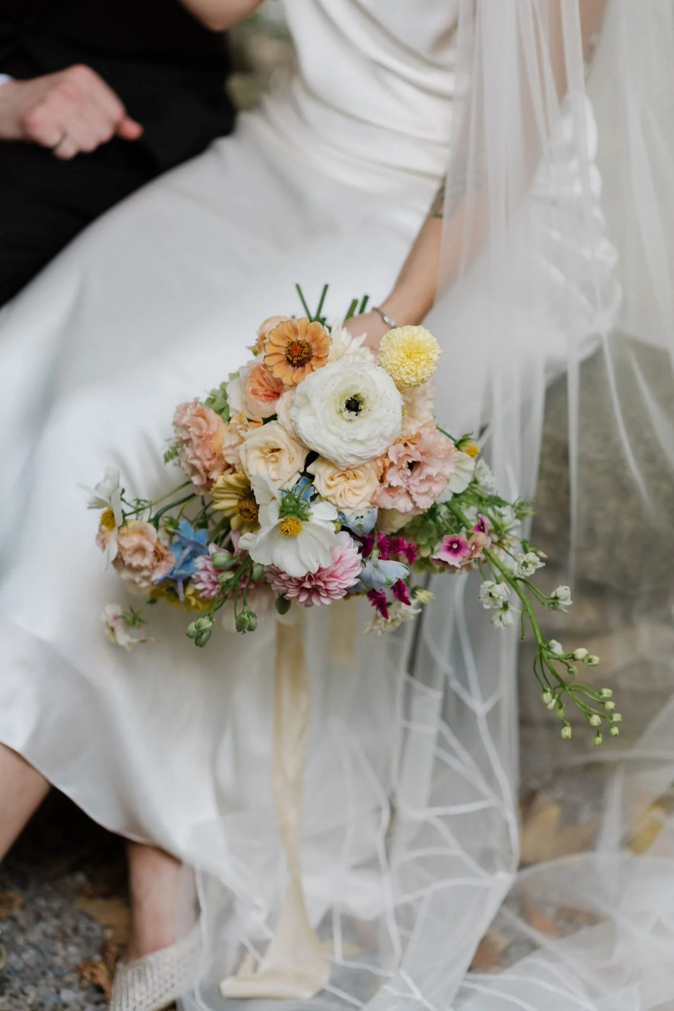 A bride holding a colorful bouquet of flowers at a wedding.