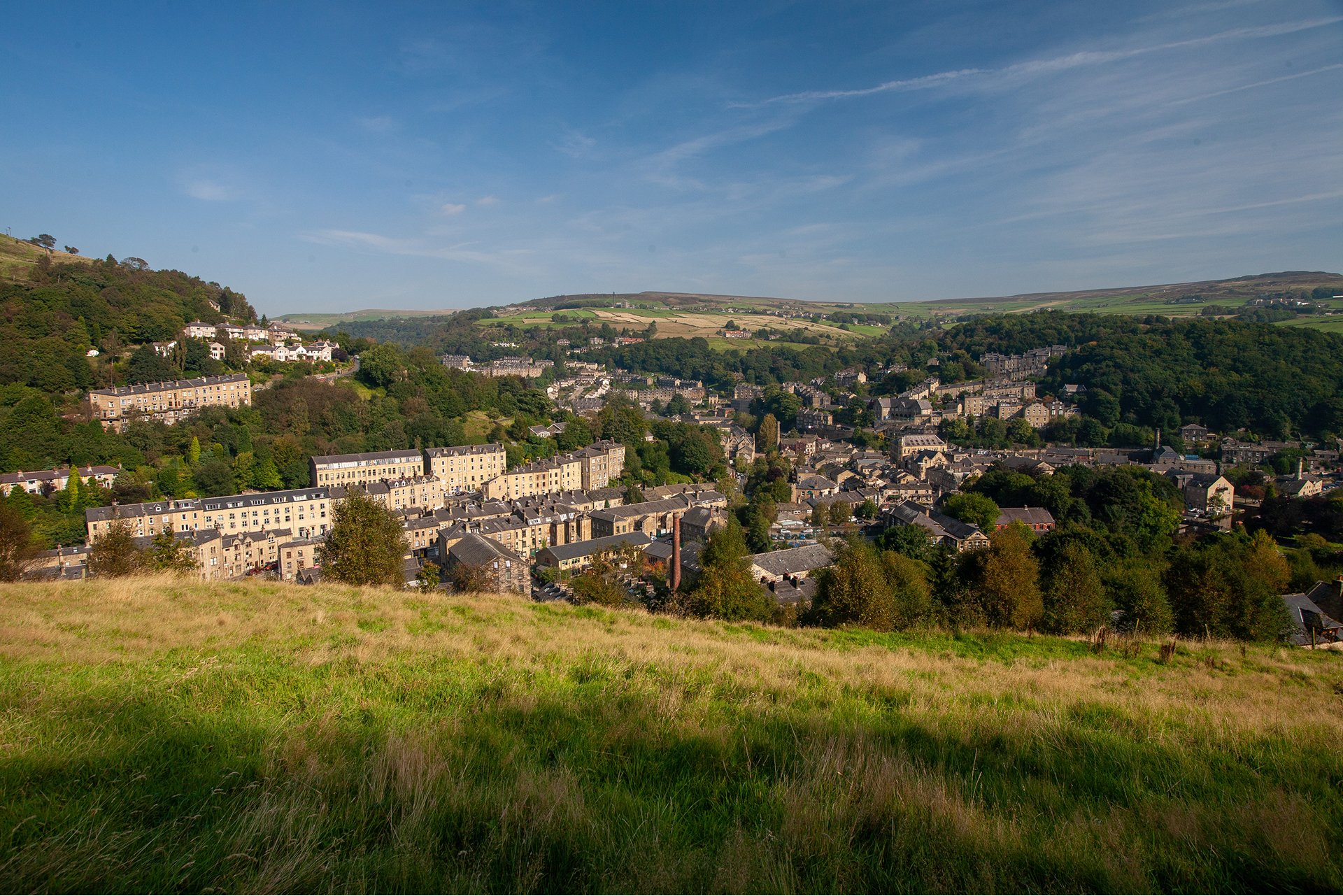 Aerial view of Hebden Bridge town from hillside, showing stone terraced houses and wooded valley in West Yorkshire