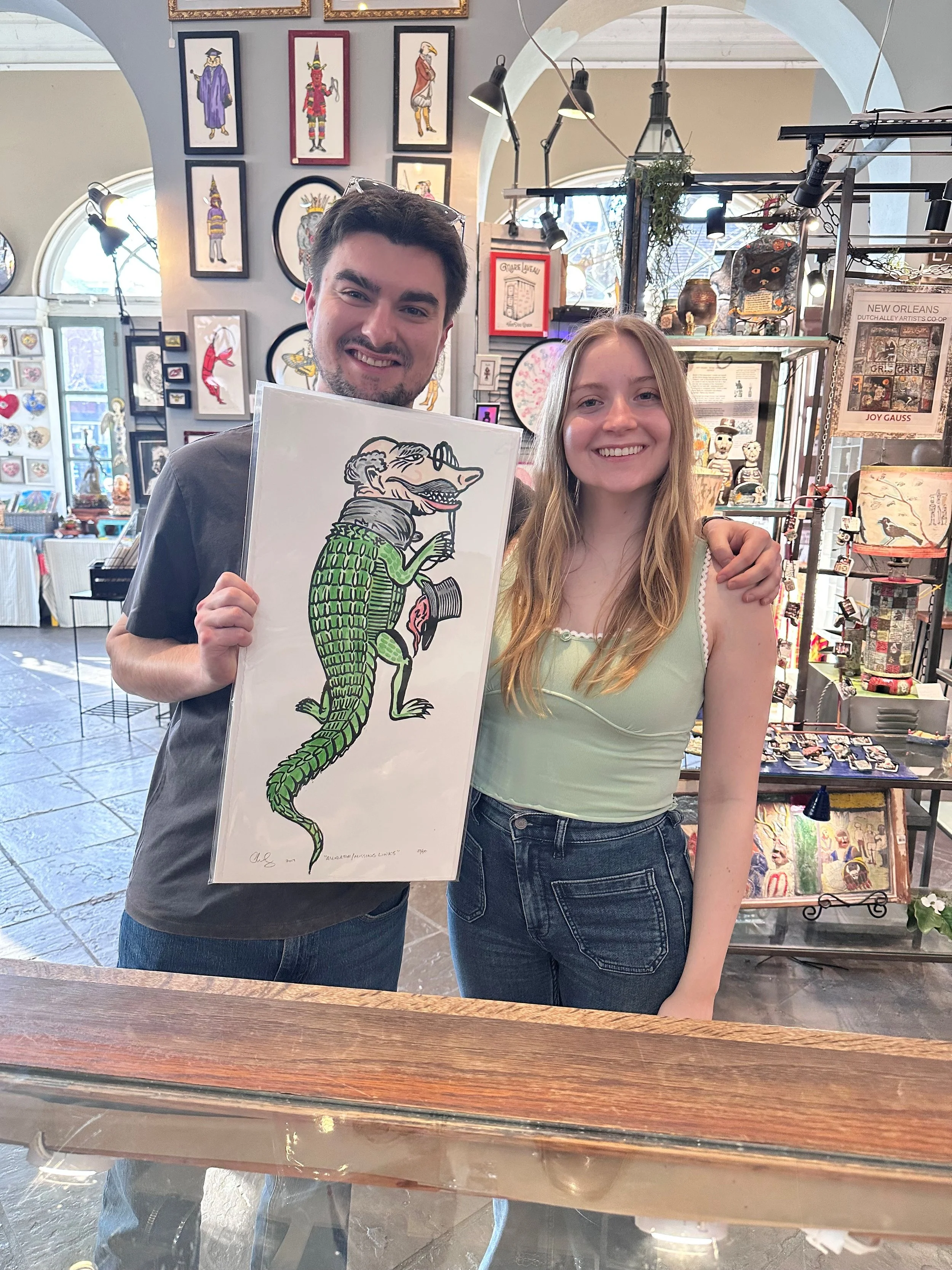 A man and a woman holding up a piece of artwork they purchsed.