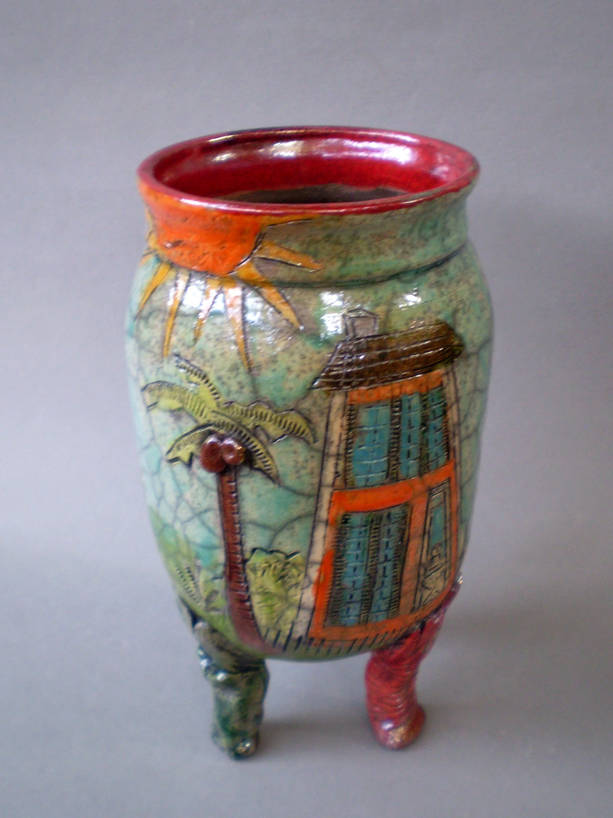 colorful raku fired jar with red rim and three legs