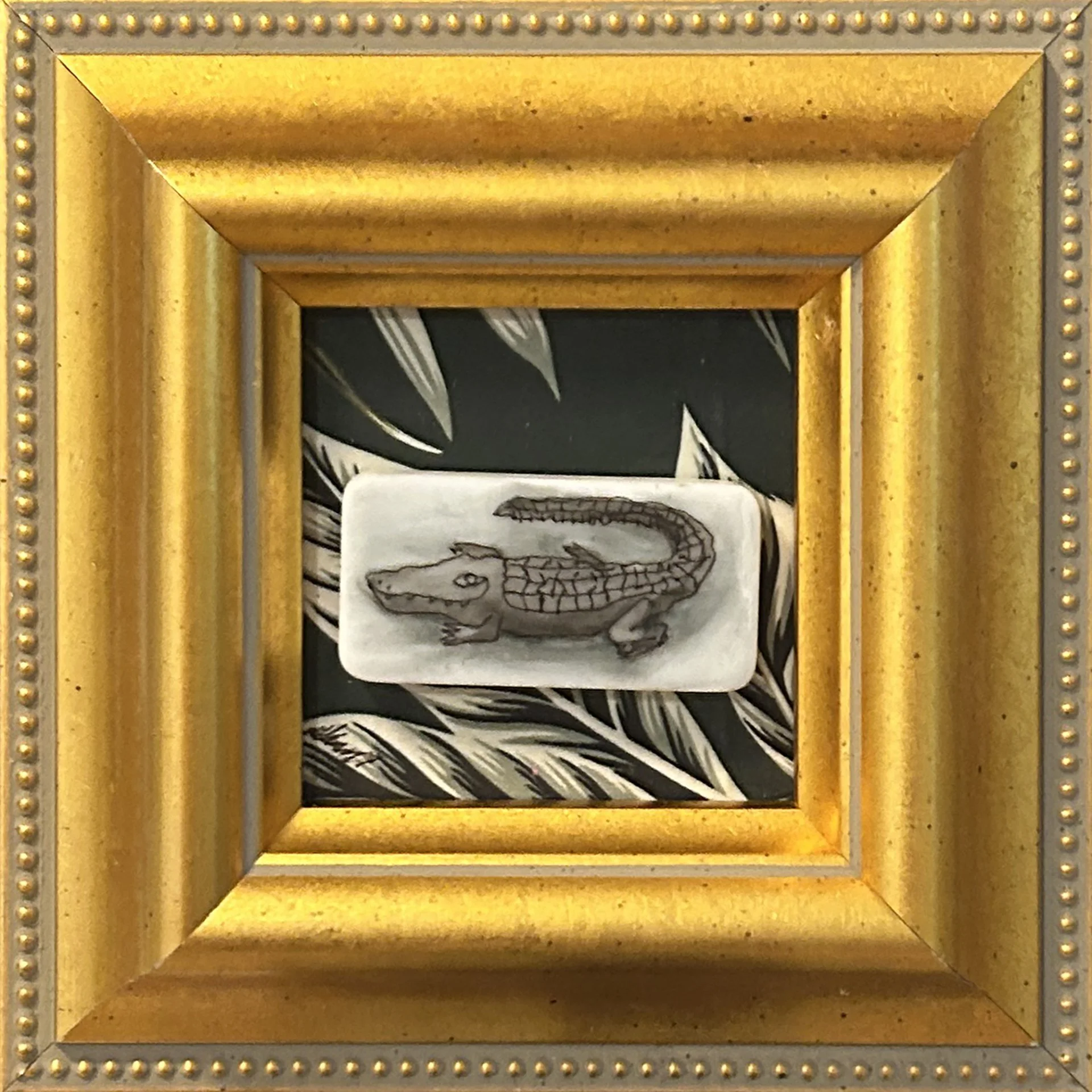 Alligator painted on domino, mounted on painted canvas and framed