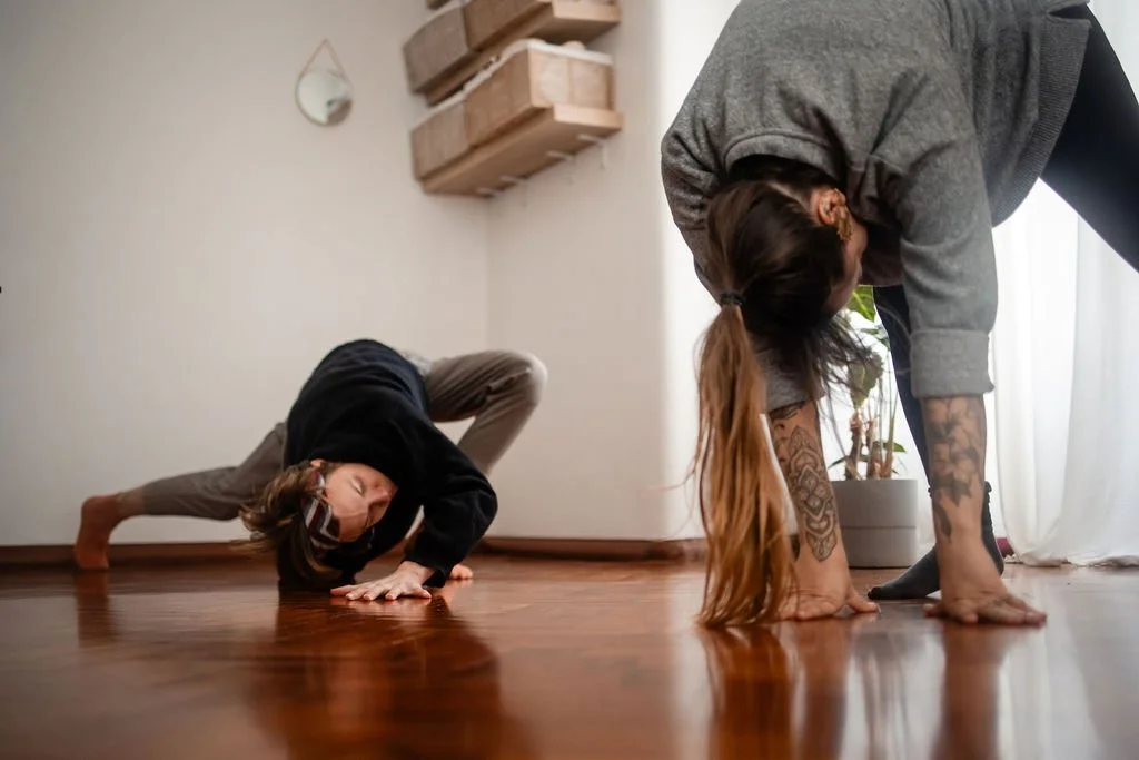 twowomenmovingonastudiofloortheirhandareonthegroundandeyesclosed