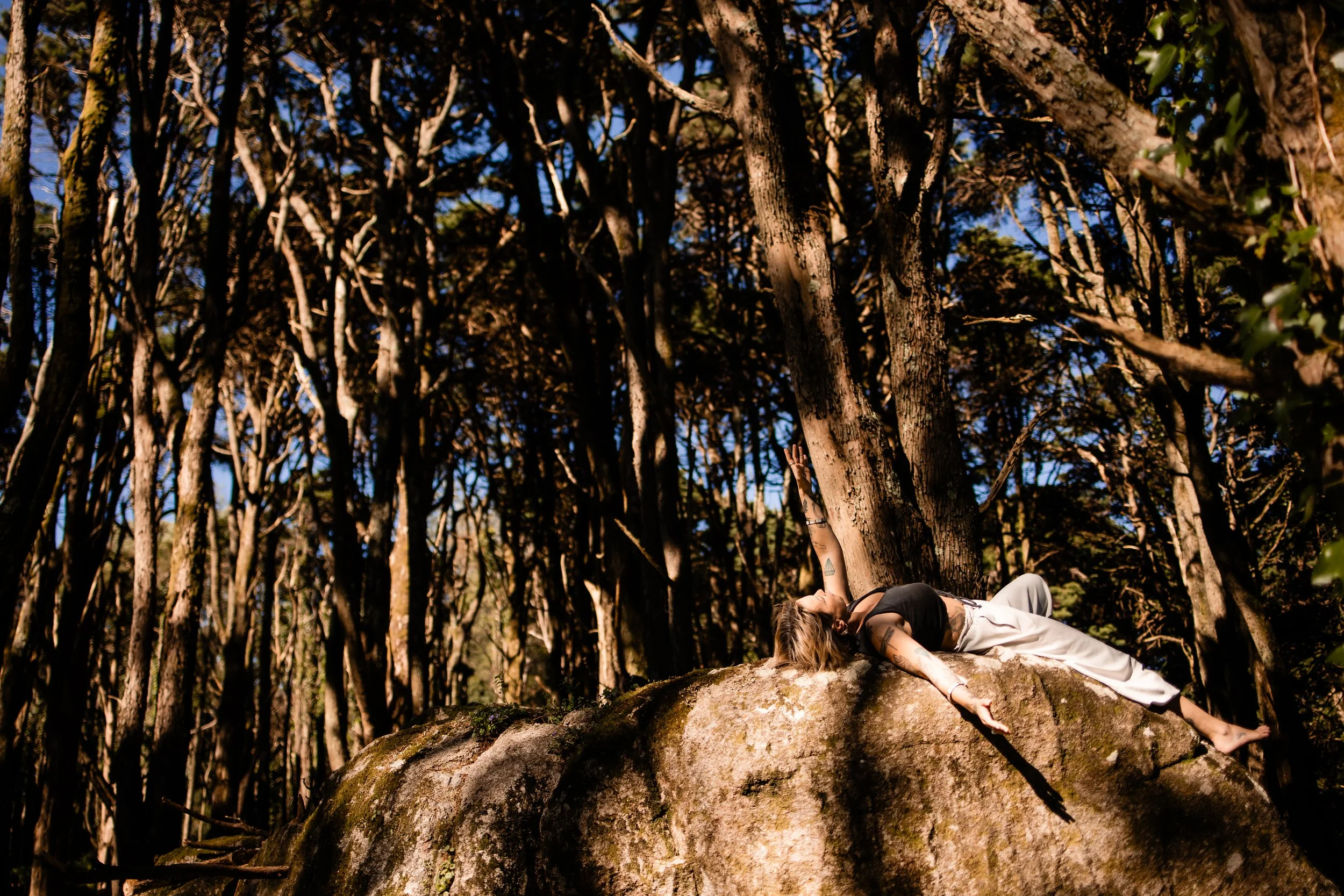 womanlayingonrockinforestwithsunlight