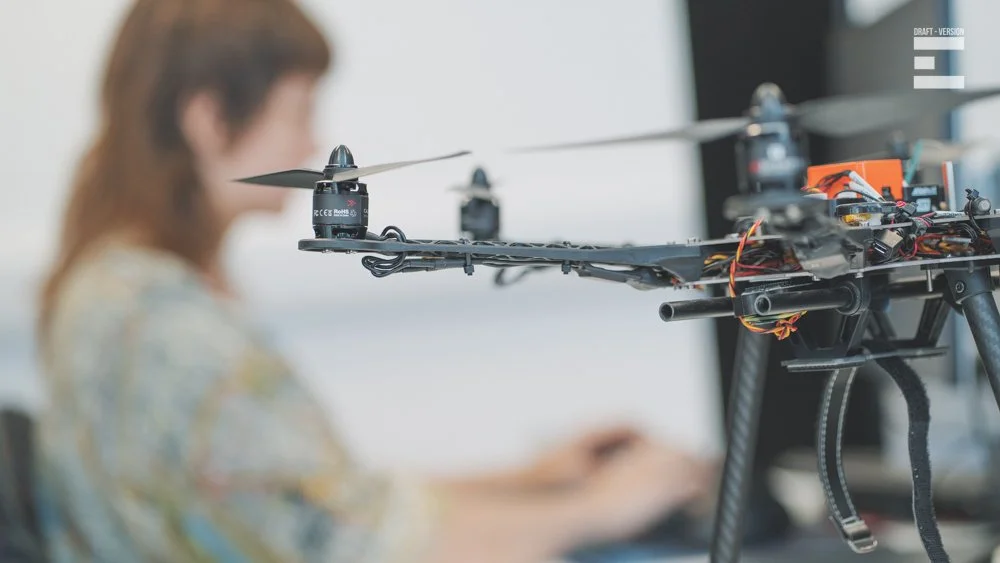 A person working on a drone with propellers, in a workshop or lab.