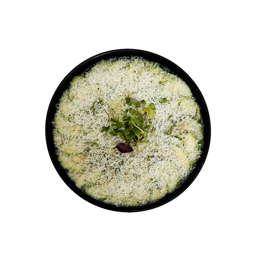 A black bowl filled with a dish topped with shredded cheese and garnished with microgreens.