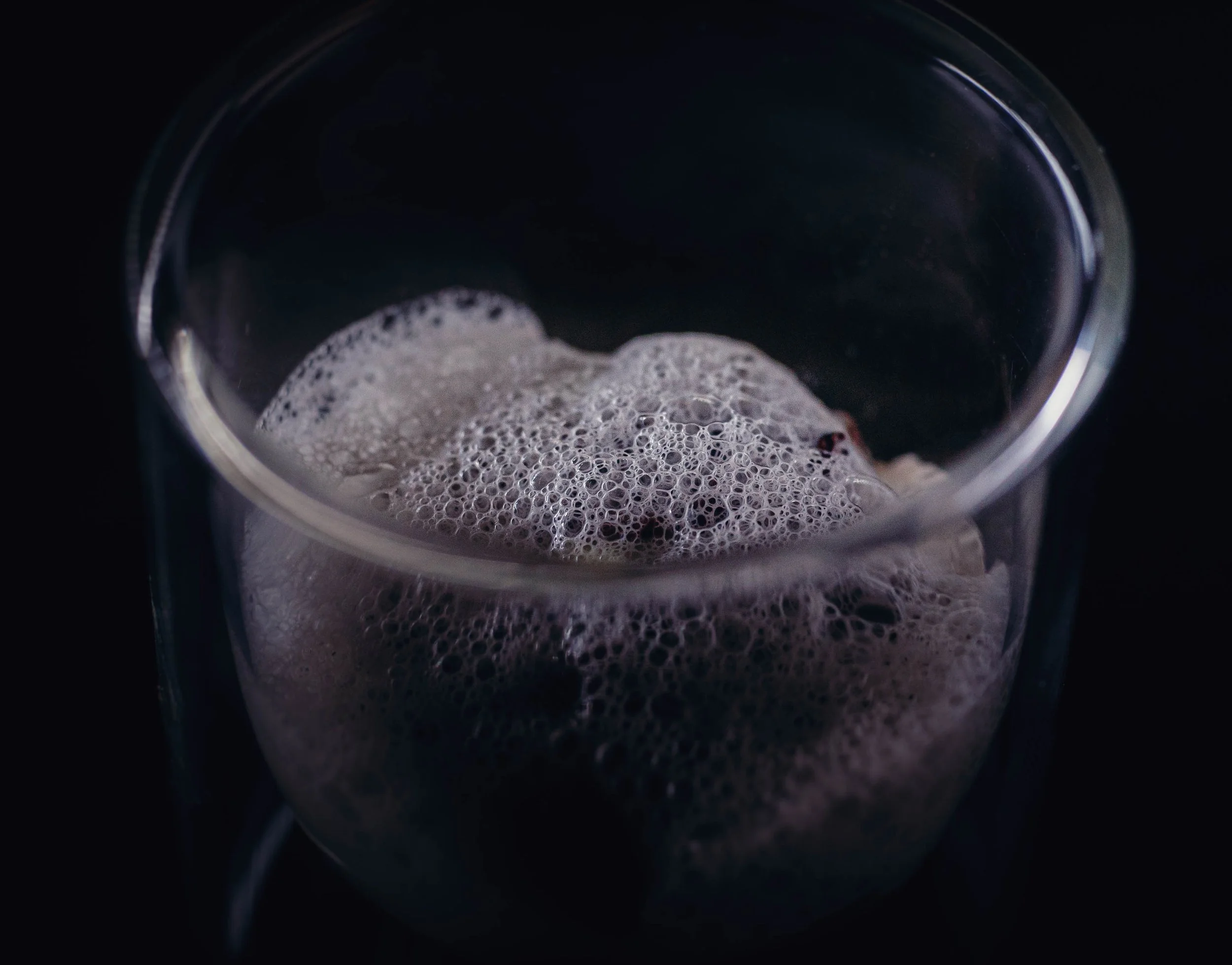 Un verre contenant une boisson gazeuse avec des bulles et de la mousse à la surface.