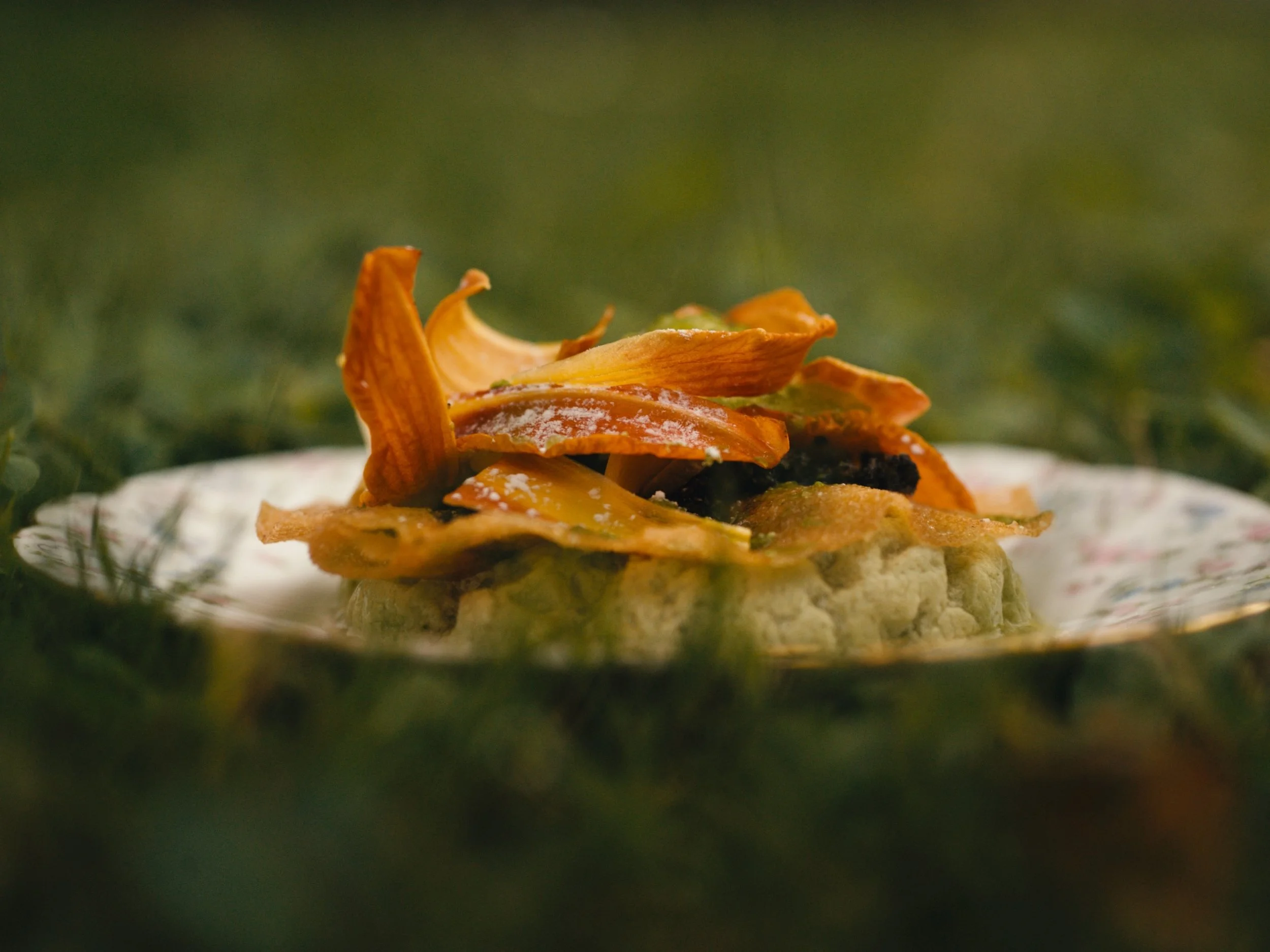 Un plat du menu signature dans une jolie assiette vintage posée dans l'herbe