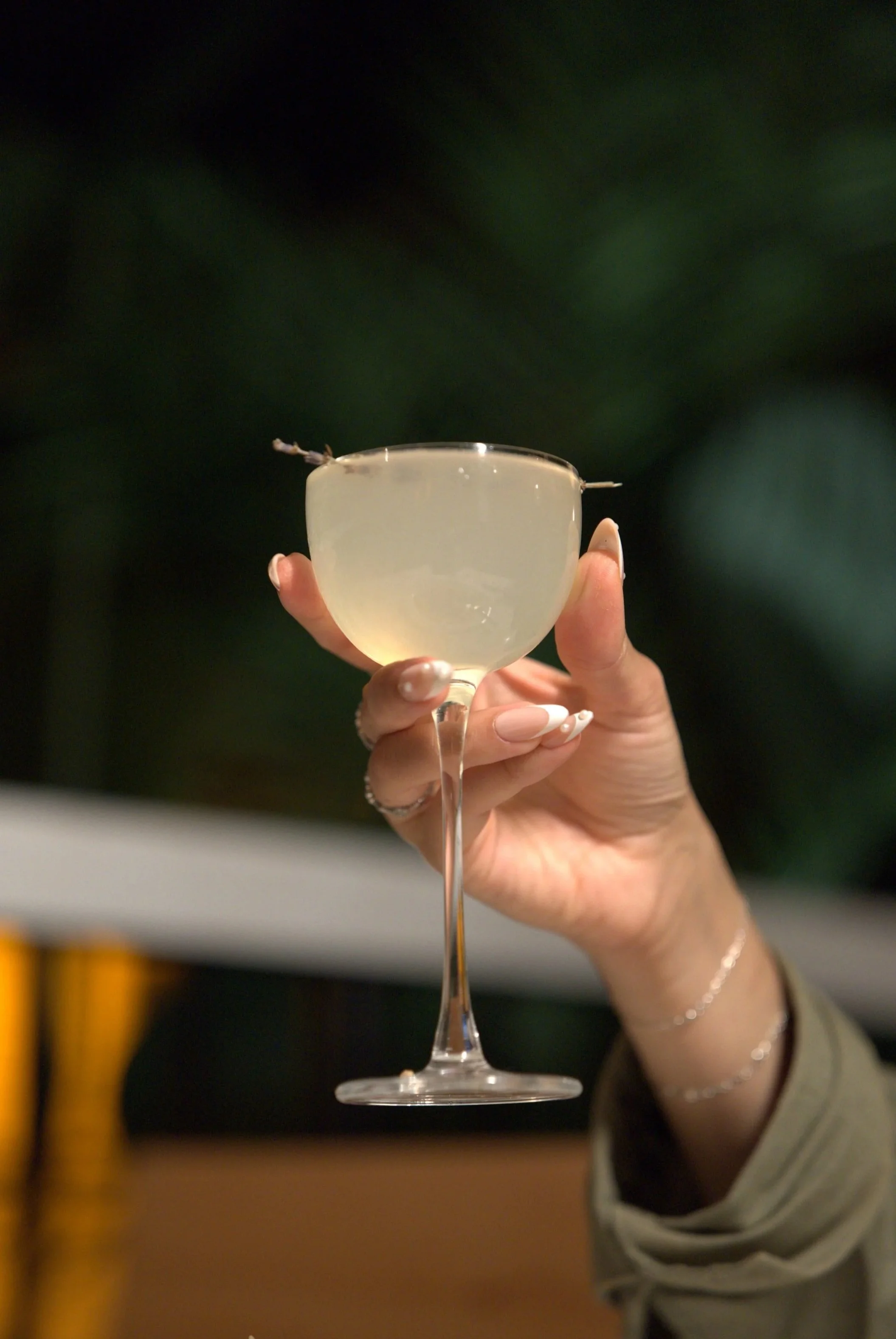 A guest holding a Tulum-inspired craft cocktail in a coupe glass, capturing the vibrant nightlife and date night atmosphere in Kendall Park.