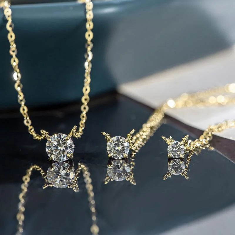 Gold jewelry set with a necklace and earrings, featuring large round diamonds on a reflective black surface.