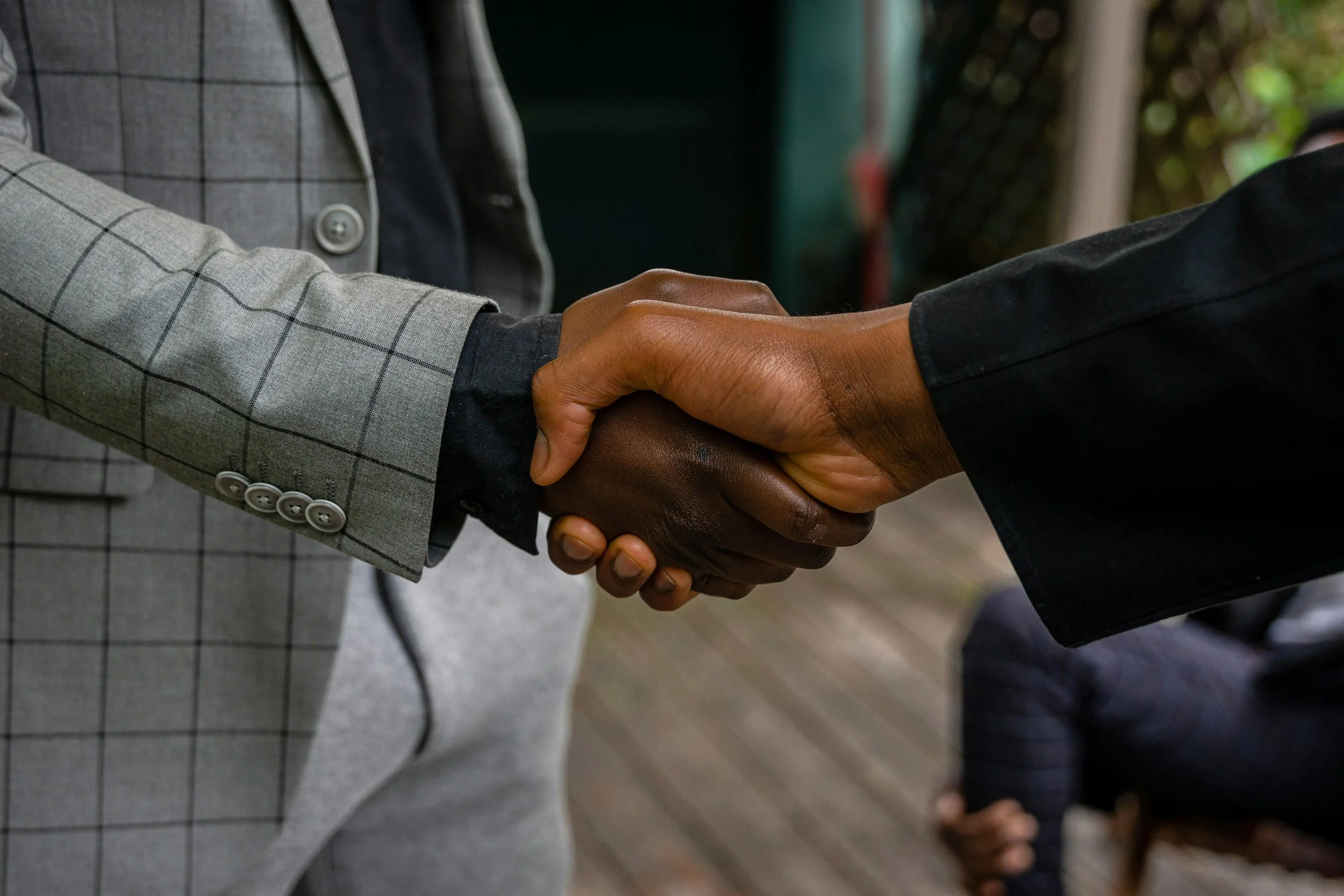 Two people in business attire shaking hands outdoors.