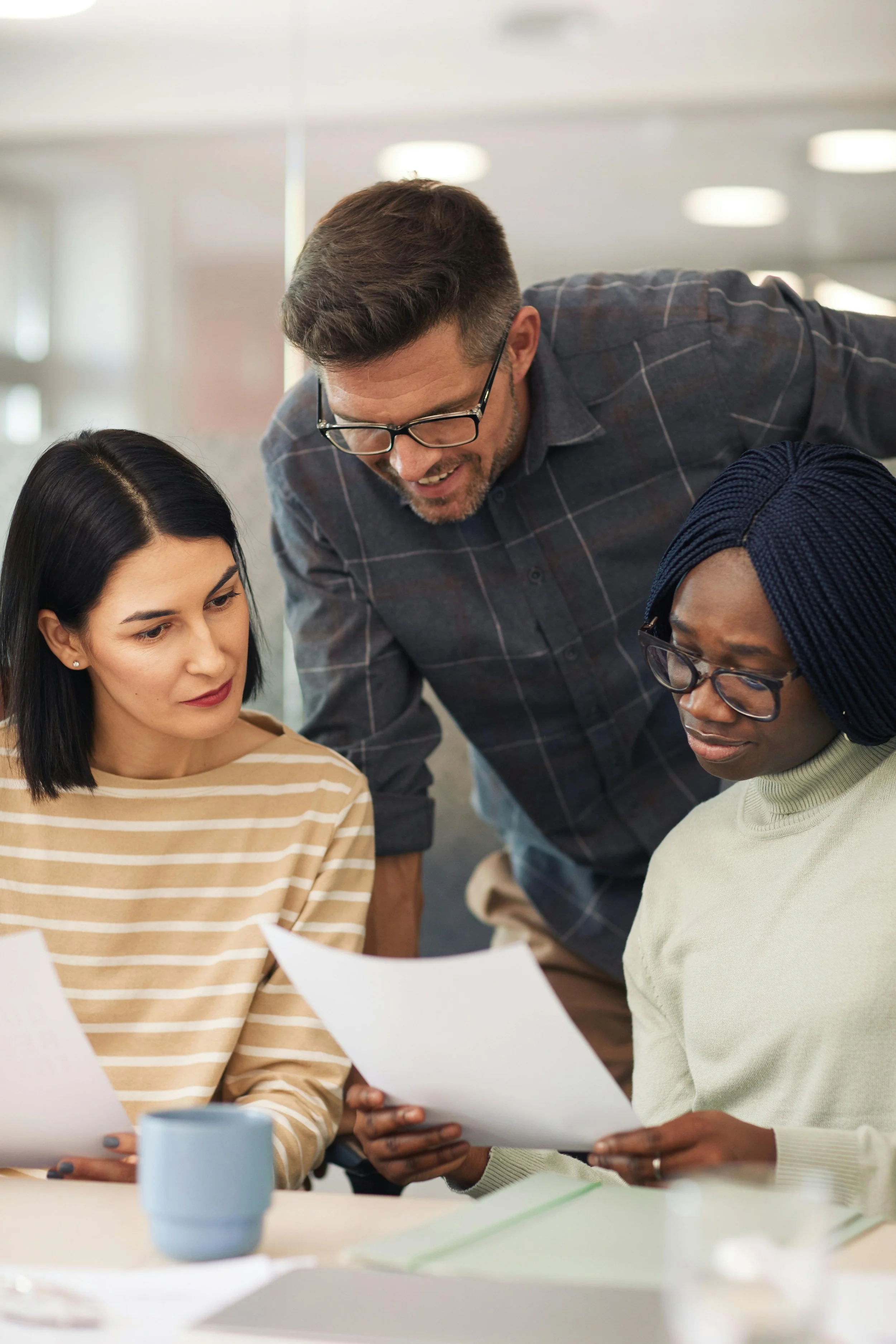 Three colleagues looking at documents together in an office setting.