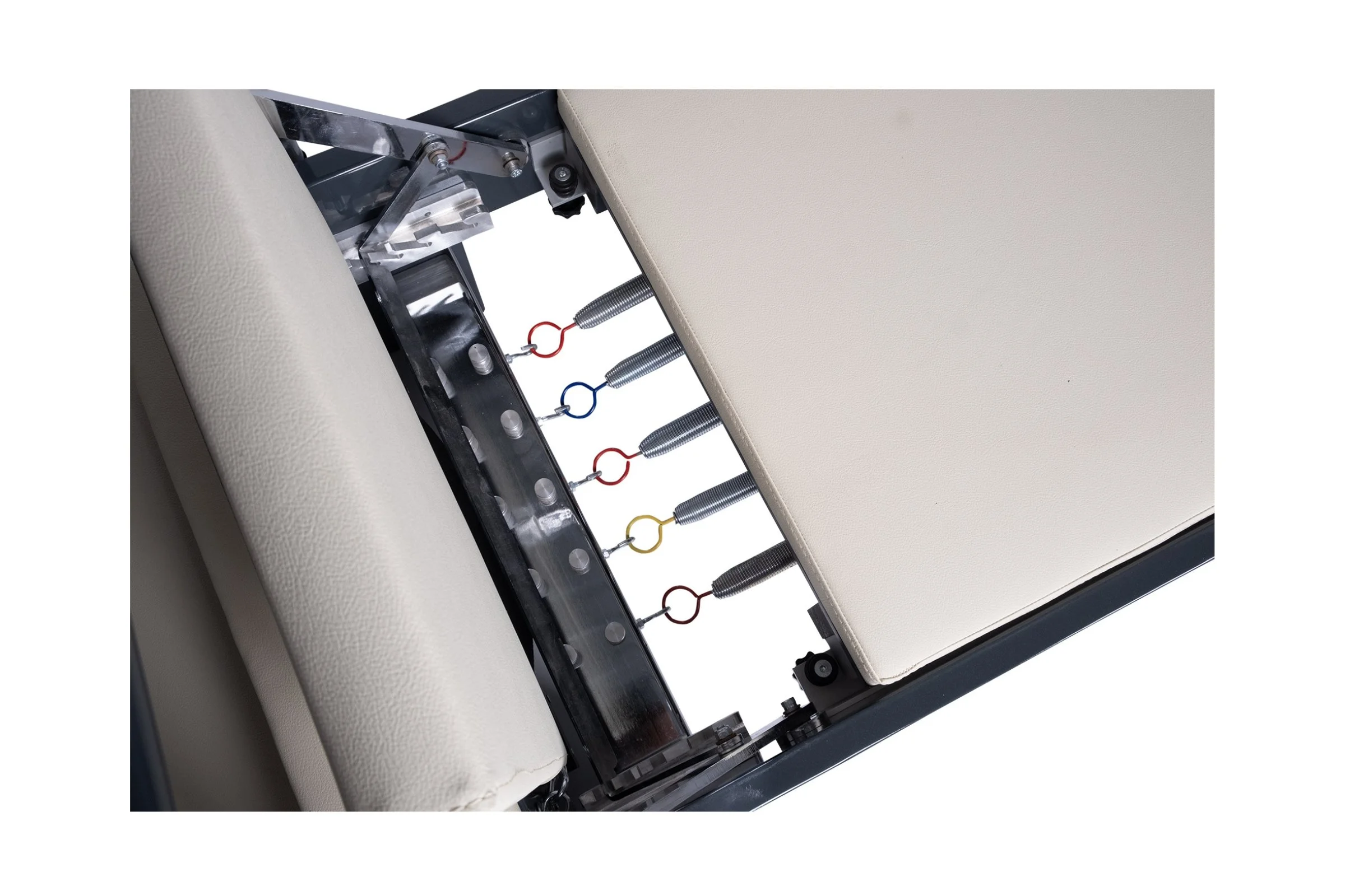 Close-up of a medical examination table showing metal springs, rings, and beige padded surfaces.