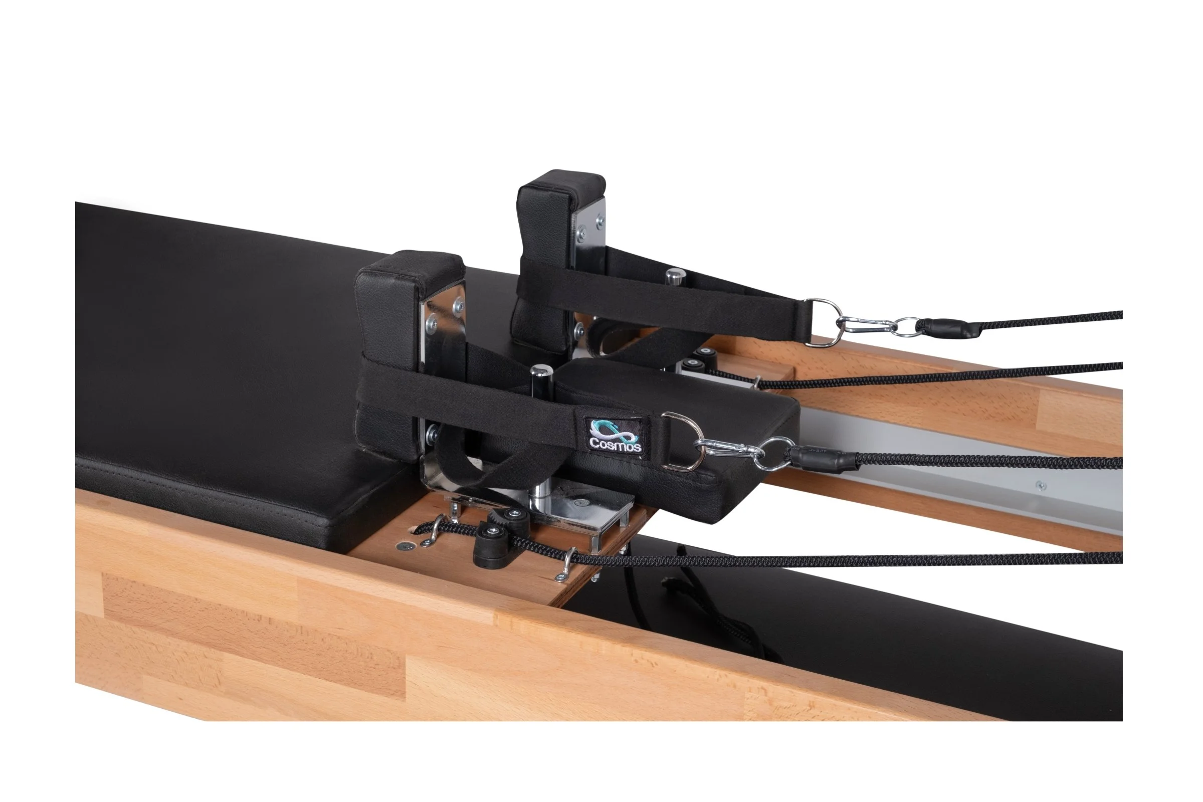 A piece of equipment with a black padded pad, metal supports, and straps with the Cosmos logo, attached to a wooden surface, likely used for physical therapy or exercise.