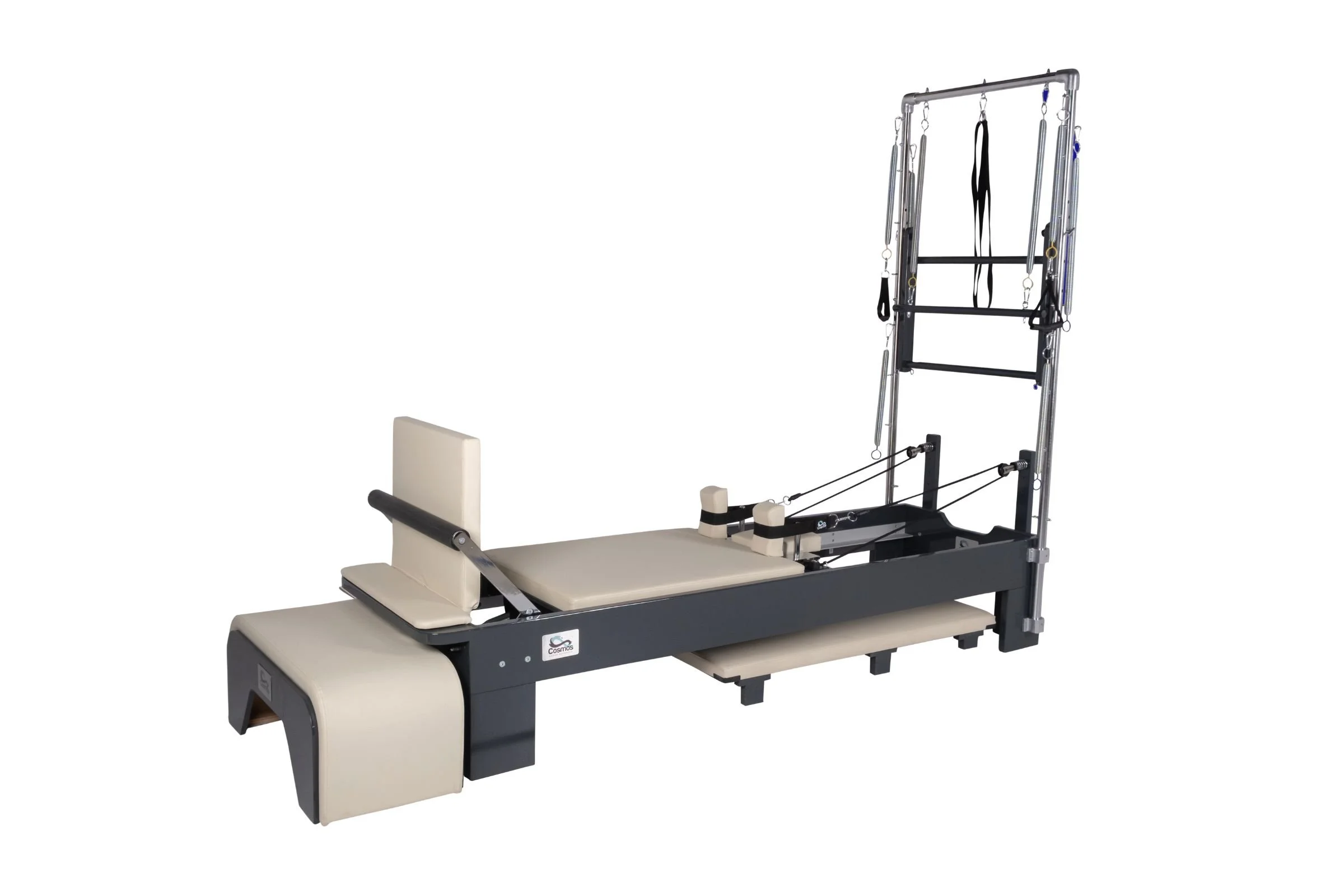 A Pilates reformer machine with a beige padded carriage, headrest, and footrest, and a metal frame with pulleys and adjustable straps.
