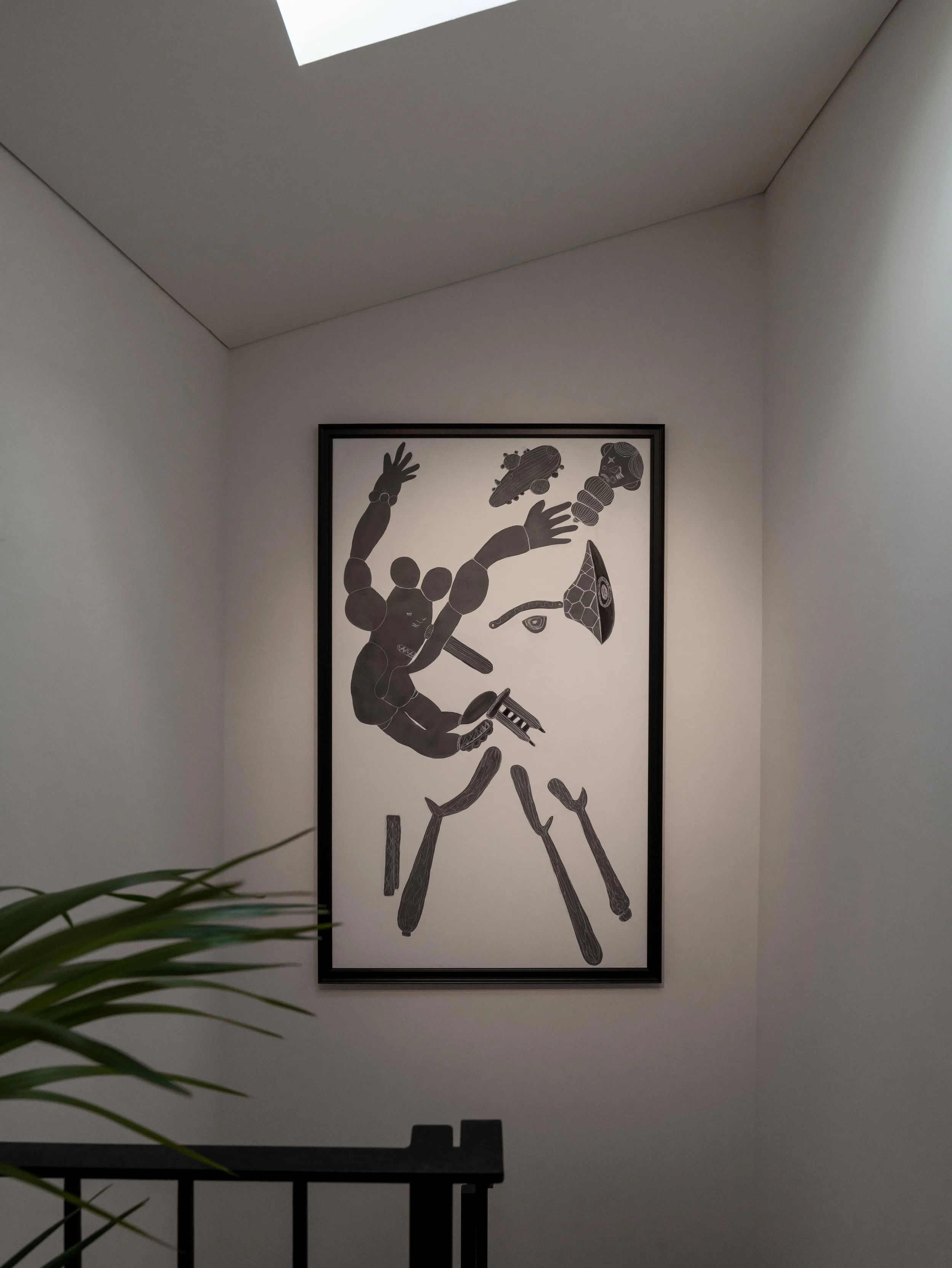 Cuadro con arte abstracto en tonos grises en una pared blanca, con formas que parecen partes del cuerpo y objetos, en un espacio interior con luz natural.