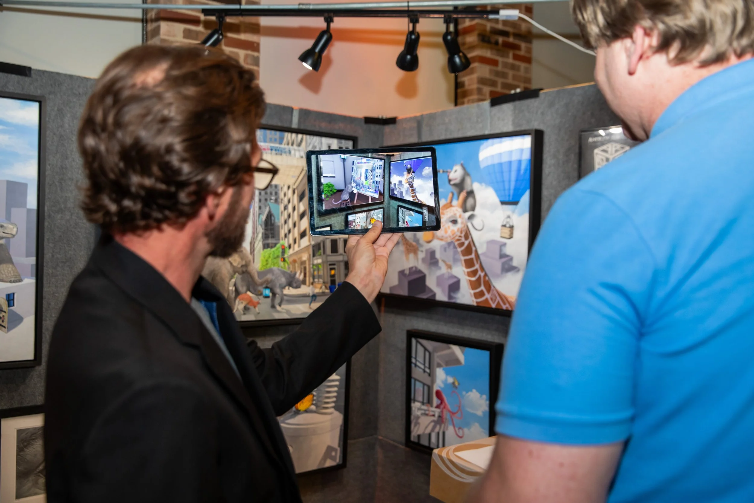Two men viewing digital art displays and photos of animals and cityscapes at an indoor exhibition.