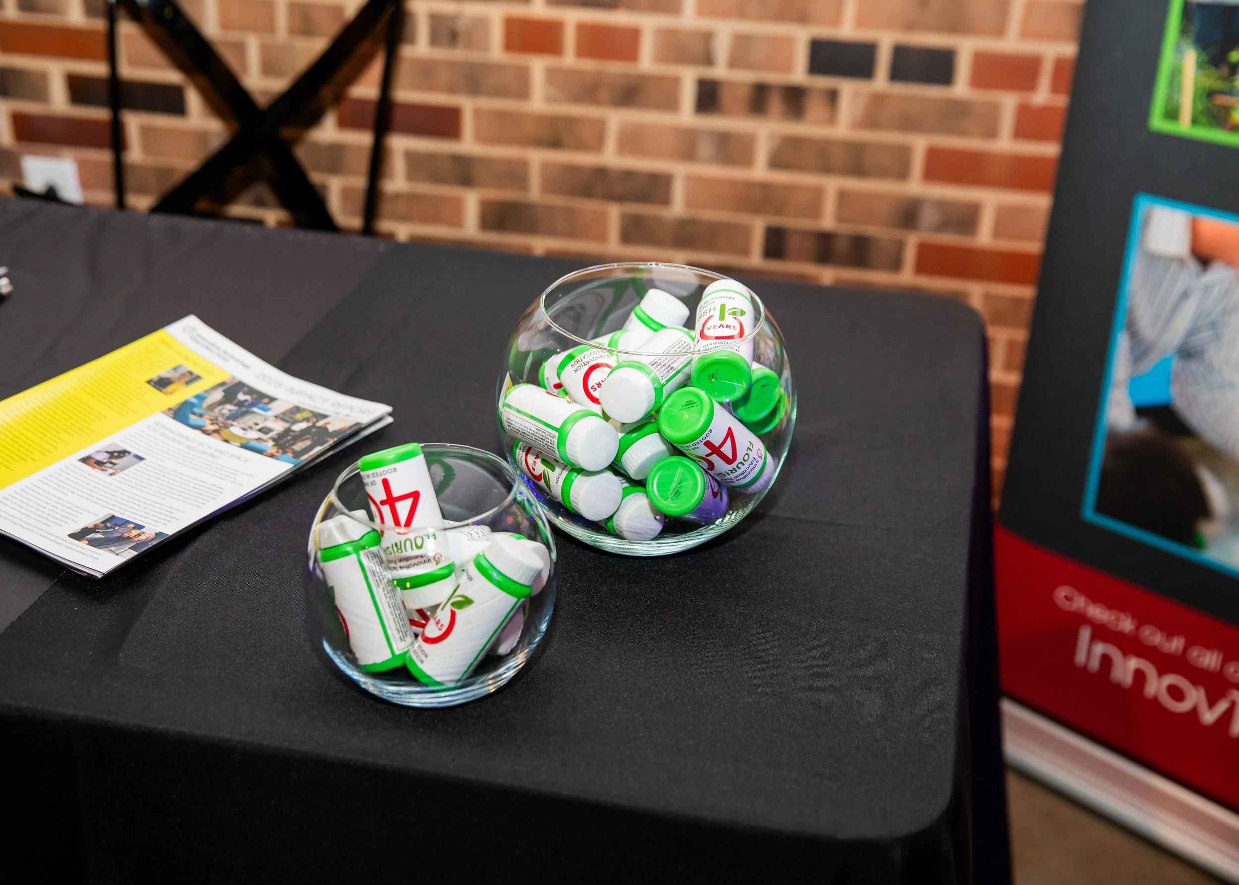 Clear glass bowls filled with small white and green bottles labeled '4' and '5 years', placed on a black table next to a yellow magazine and part of a red and blue box.