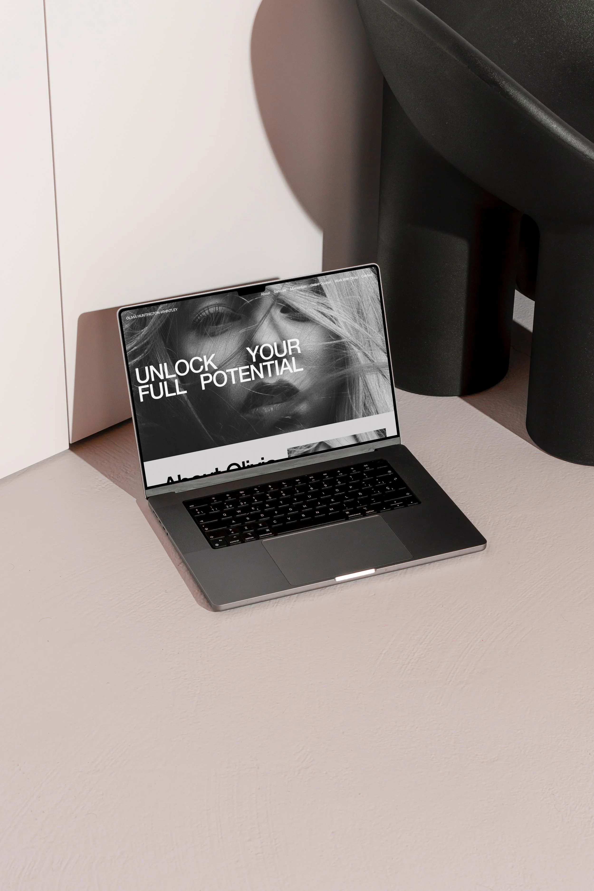A laptop on a light-colored table displaying a black-and-white image of a woman's face with the text 'Unlock Your Full Potential'.