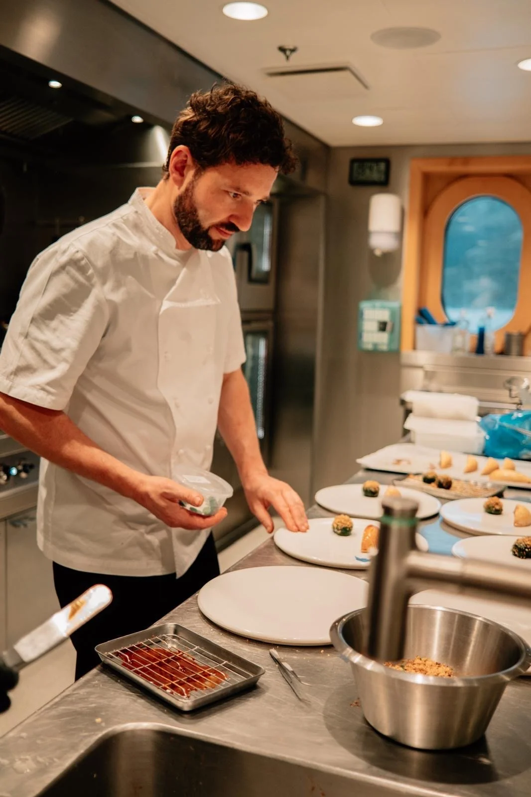 Chef preparing plated appetizers in a professional kitchen.
