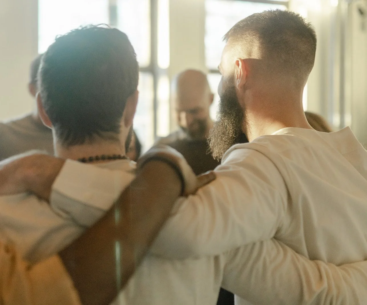 Group of diverse people having a support hug in a circle indoors.