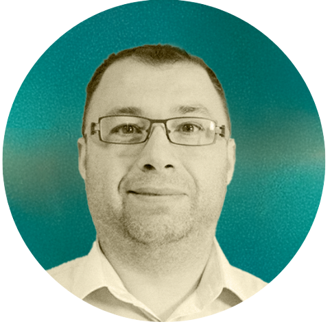 A man wearing glasses and a collared shirt, Ognen Antov, looking at the camera, with a teal background.