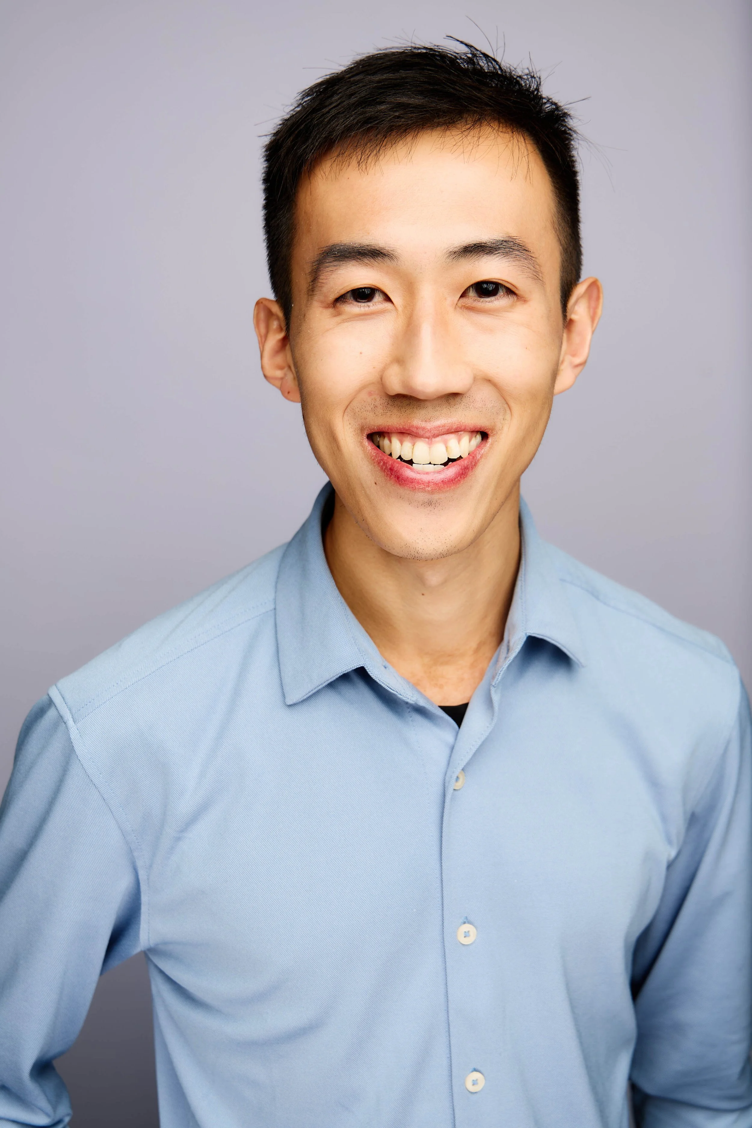 Portrait of Chenzhe Cao, wearing a light blue collared shirt, against a plain gray background.
