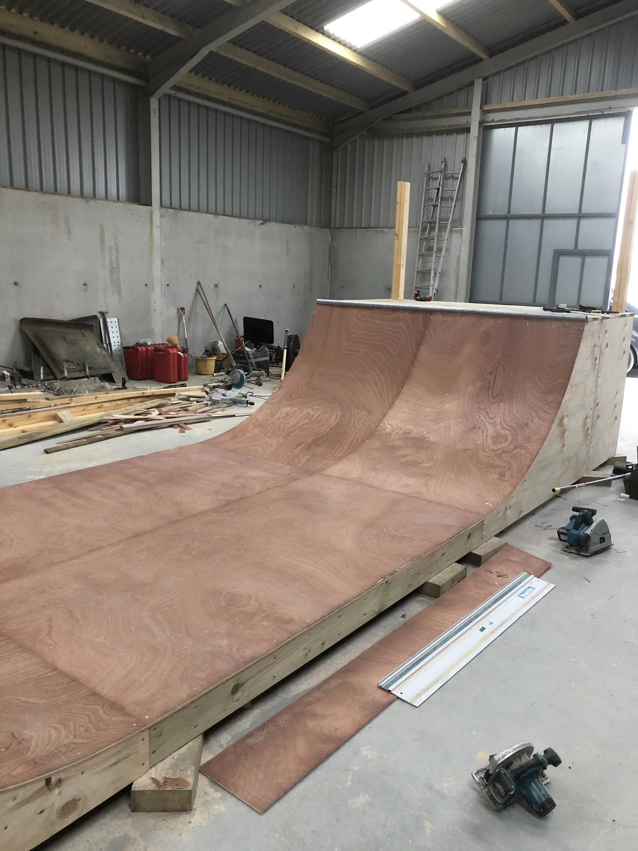 Underside of a skateboard ramp or halfpipe being constructed inside a workshop.