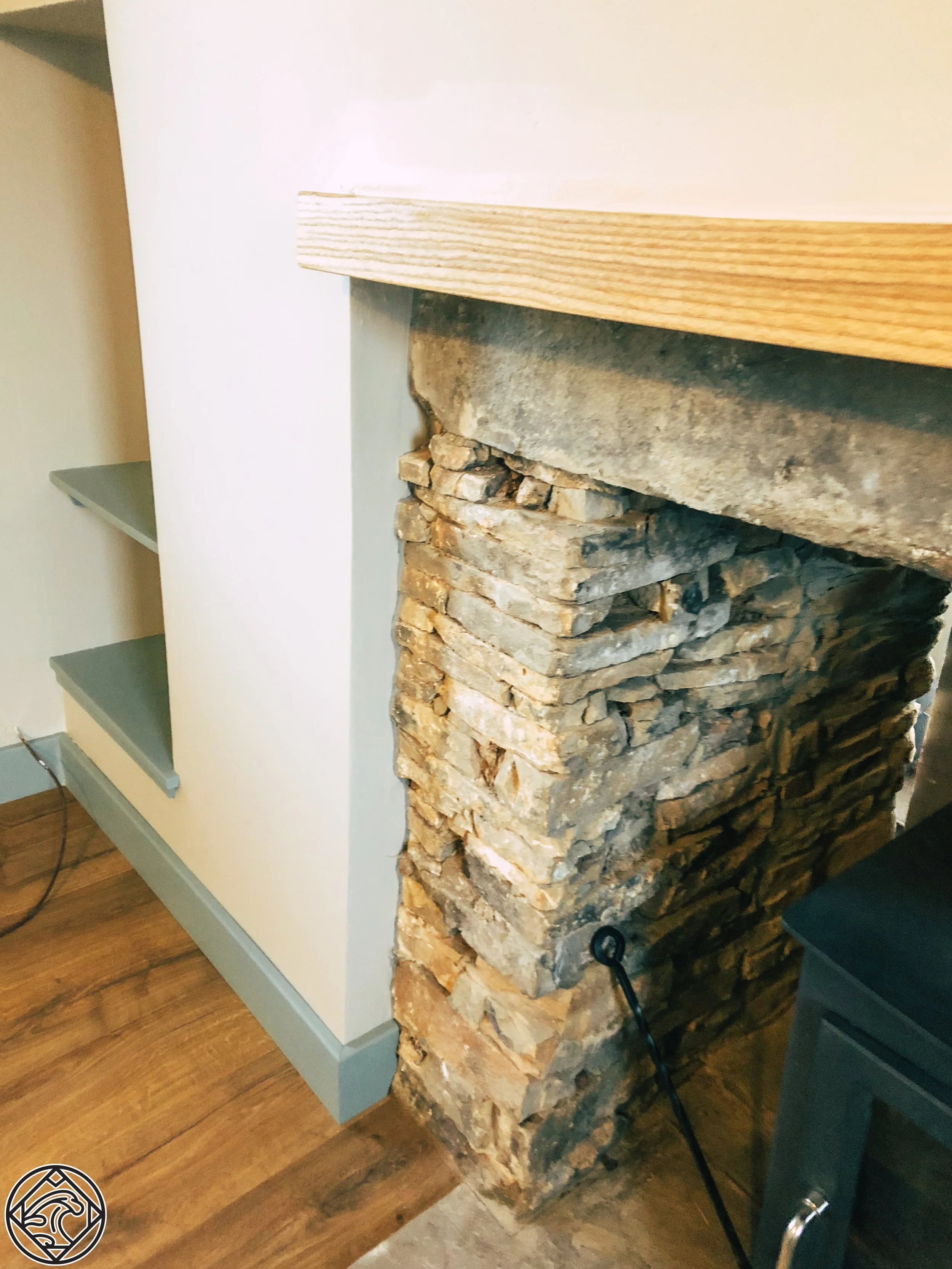 Close-up of a rustic stone fireplace with a wooden mantle.